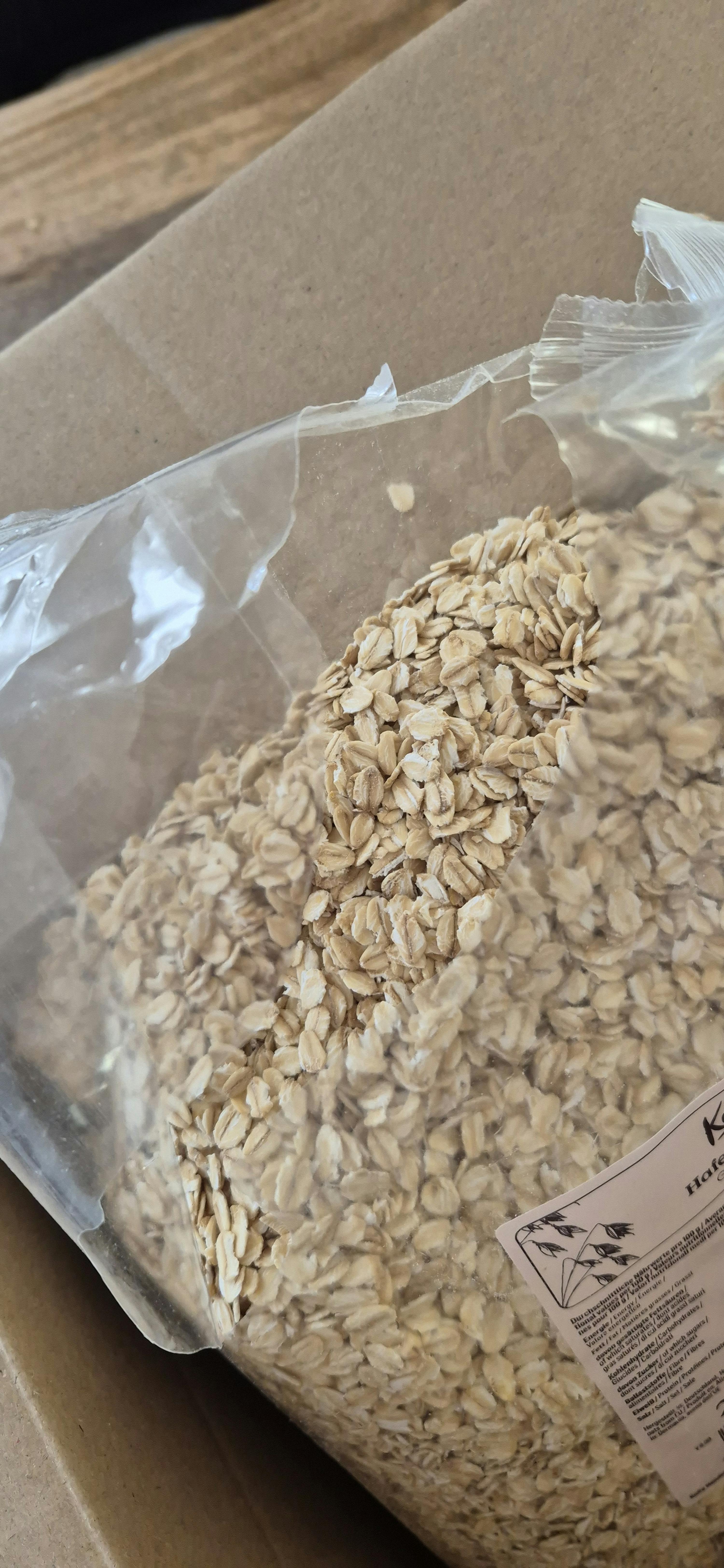 eine nahaufnahme einer durchsichtigen plastiktüte voller haferflocken, die auf einer braunen oberfläche liegt.