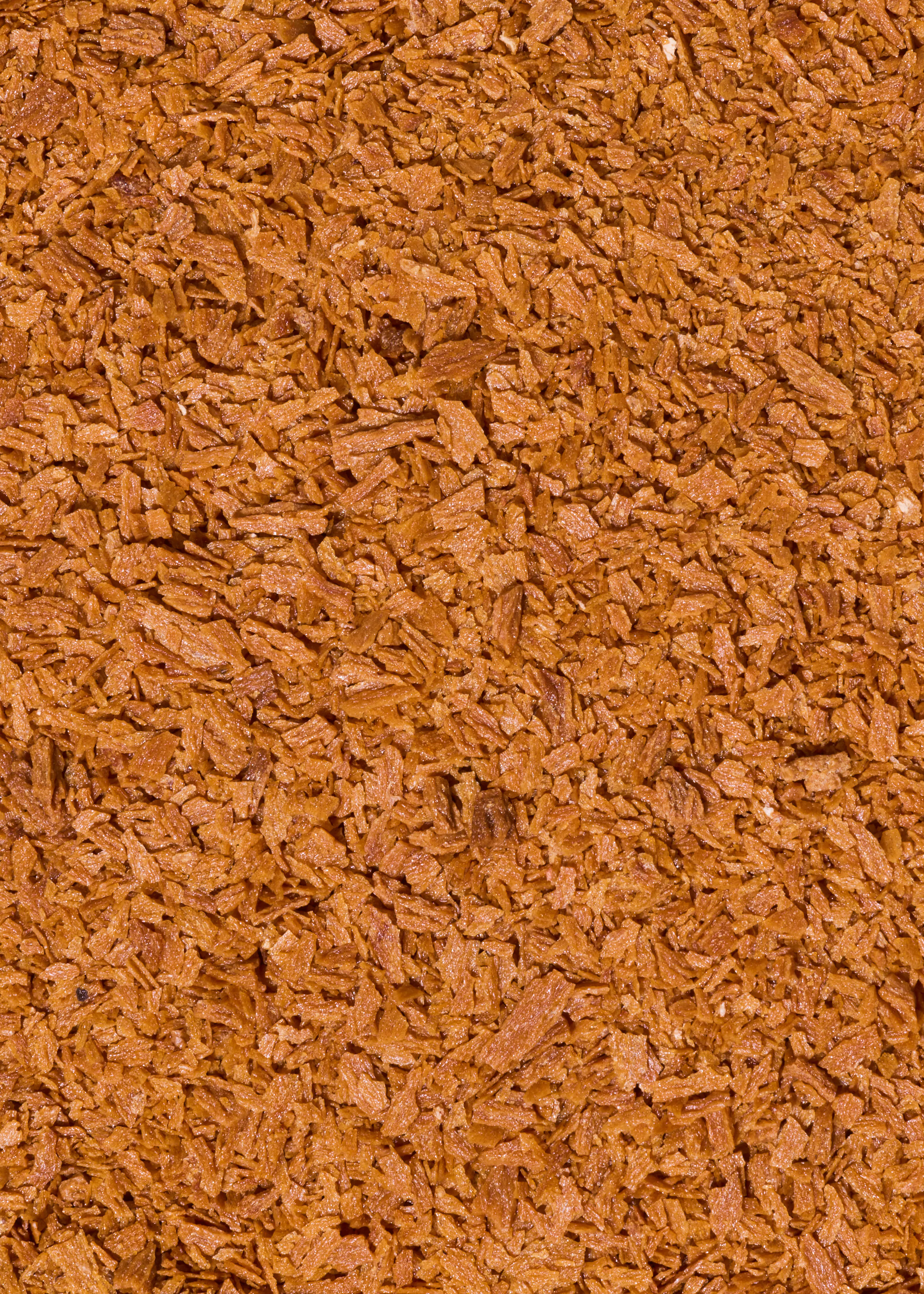 nahaufnahme einer textur aus vielen kleinen, unregelmäßig geformten braunen holzspänen.