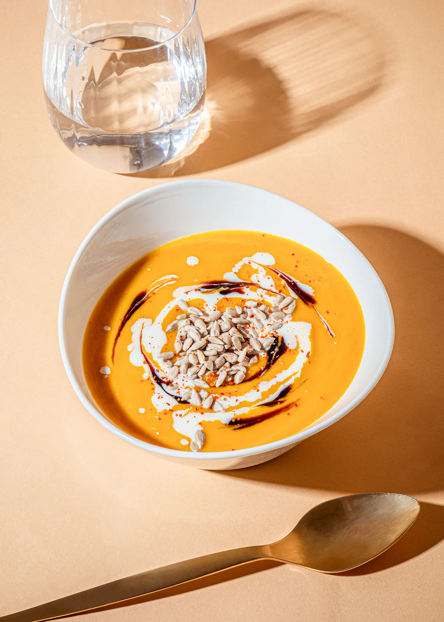 un bol de soupe avec une cuillère et un verre d' eau en arrière-plan