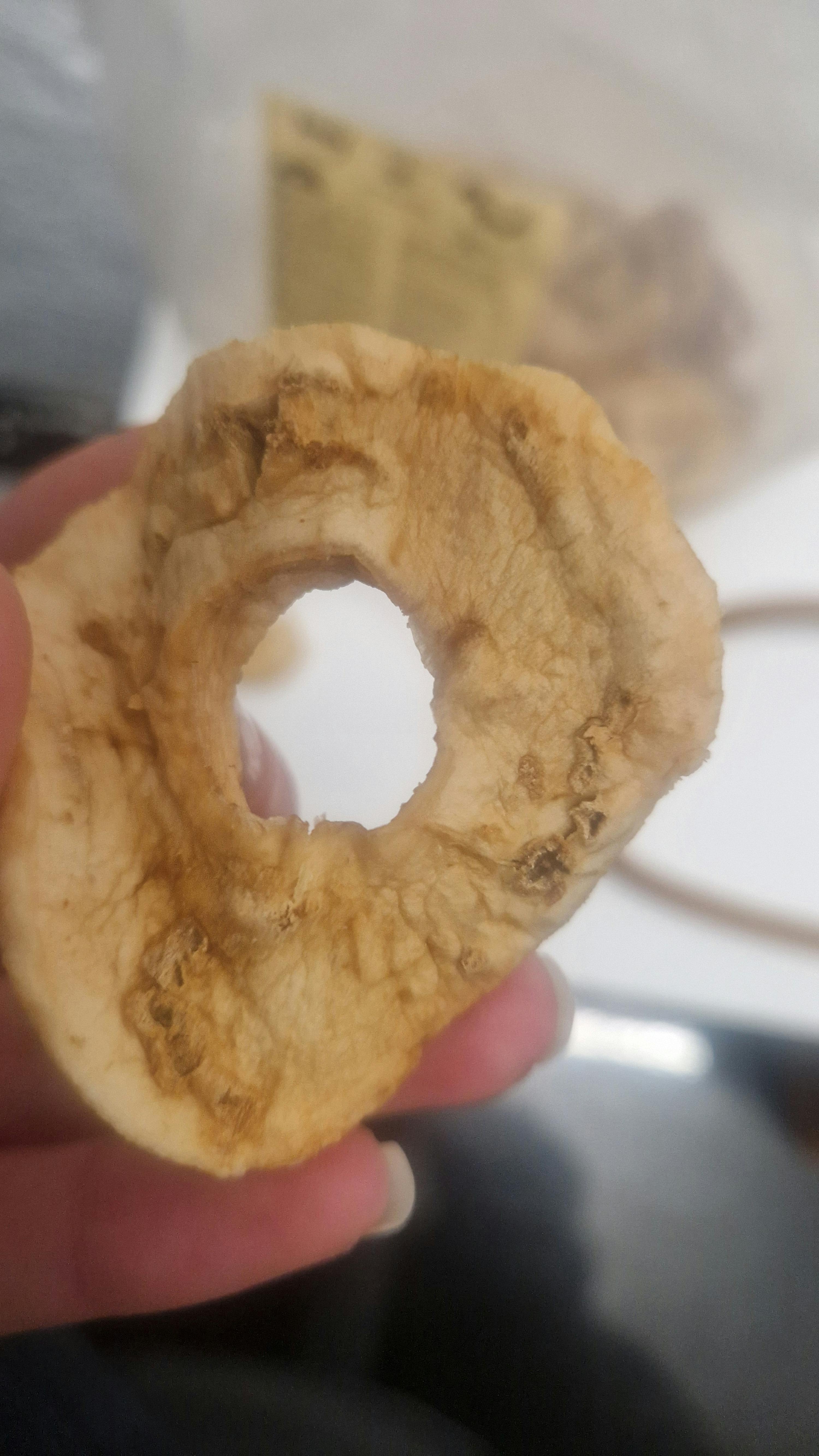 une personne tient une tranche de pomme avec un trou au milieu