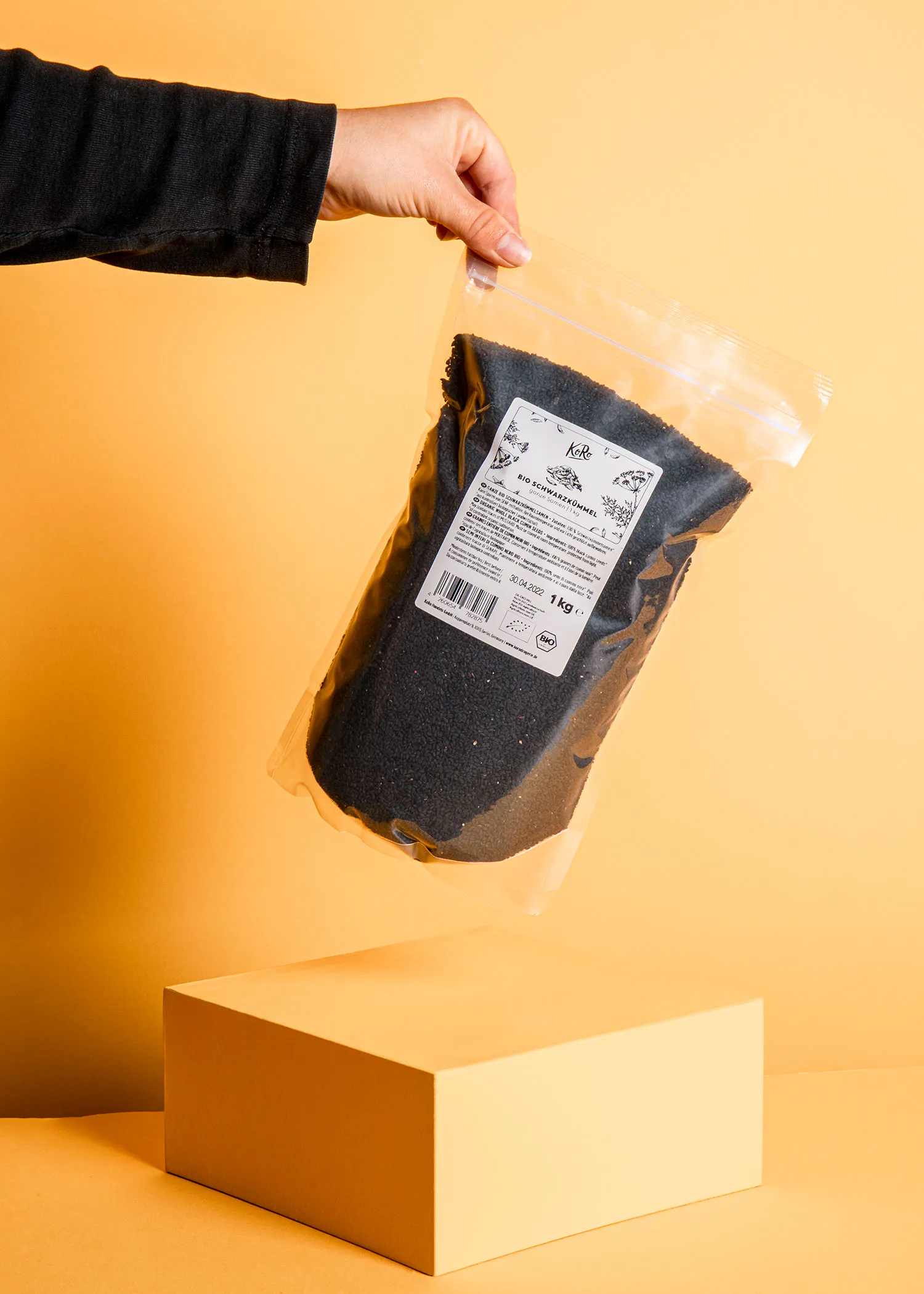 eine Person hält eine Plastiktüte mit schwarzen Sesamsamen in der Hand