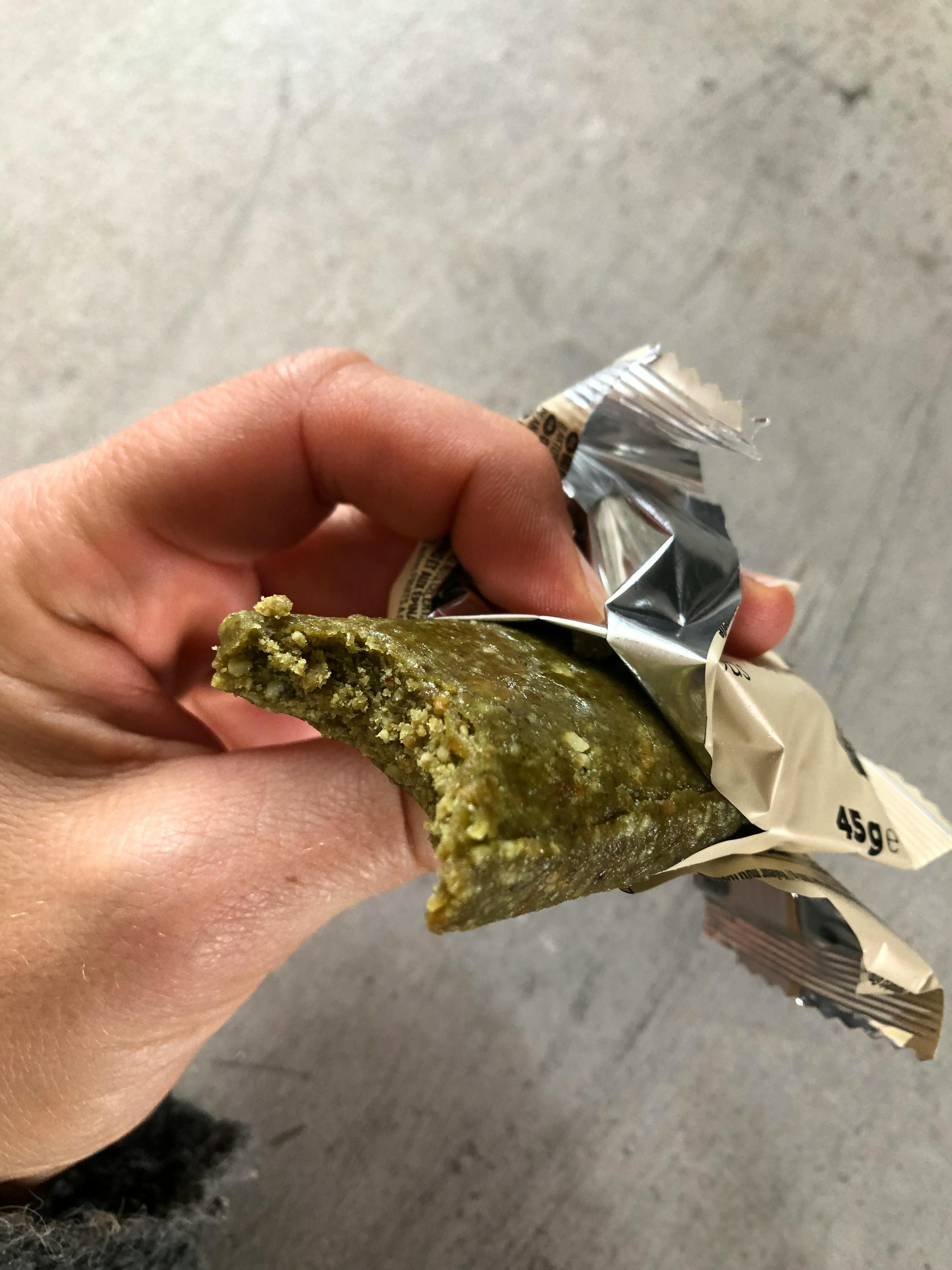 una persona tiene in mano una barretta di cioccolato verde con un morso della barretta
