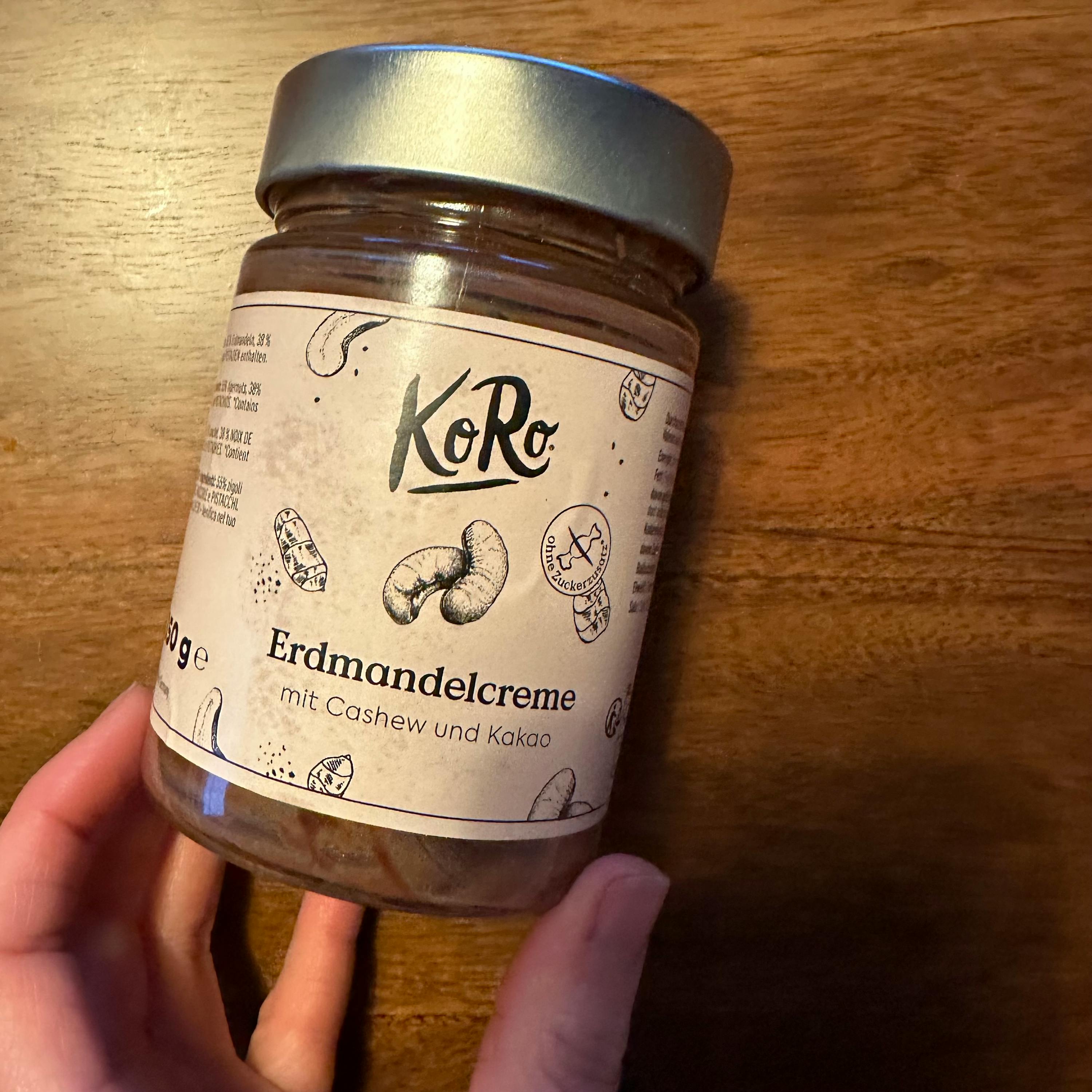 une personne tient un bocal de creme de cacahuètes et de noix de cajou