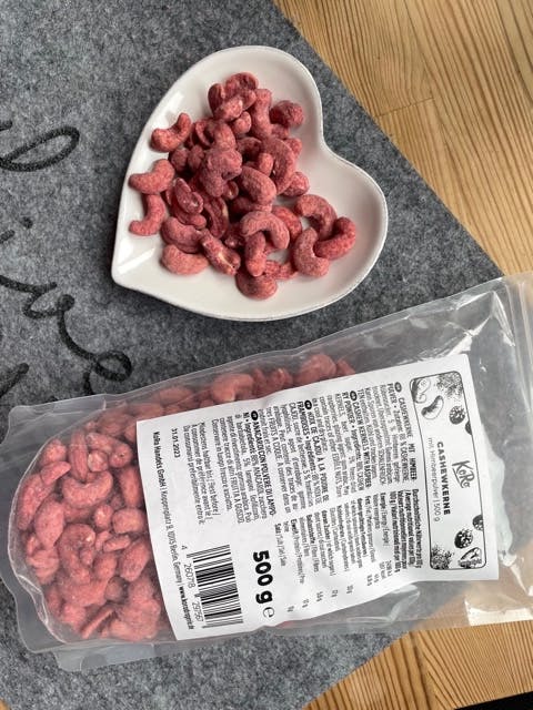 eine Schachtel Cashewkerne neben einem herzförmigen Teller mit Cashewkernen