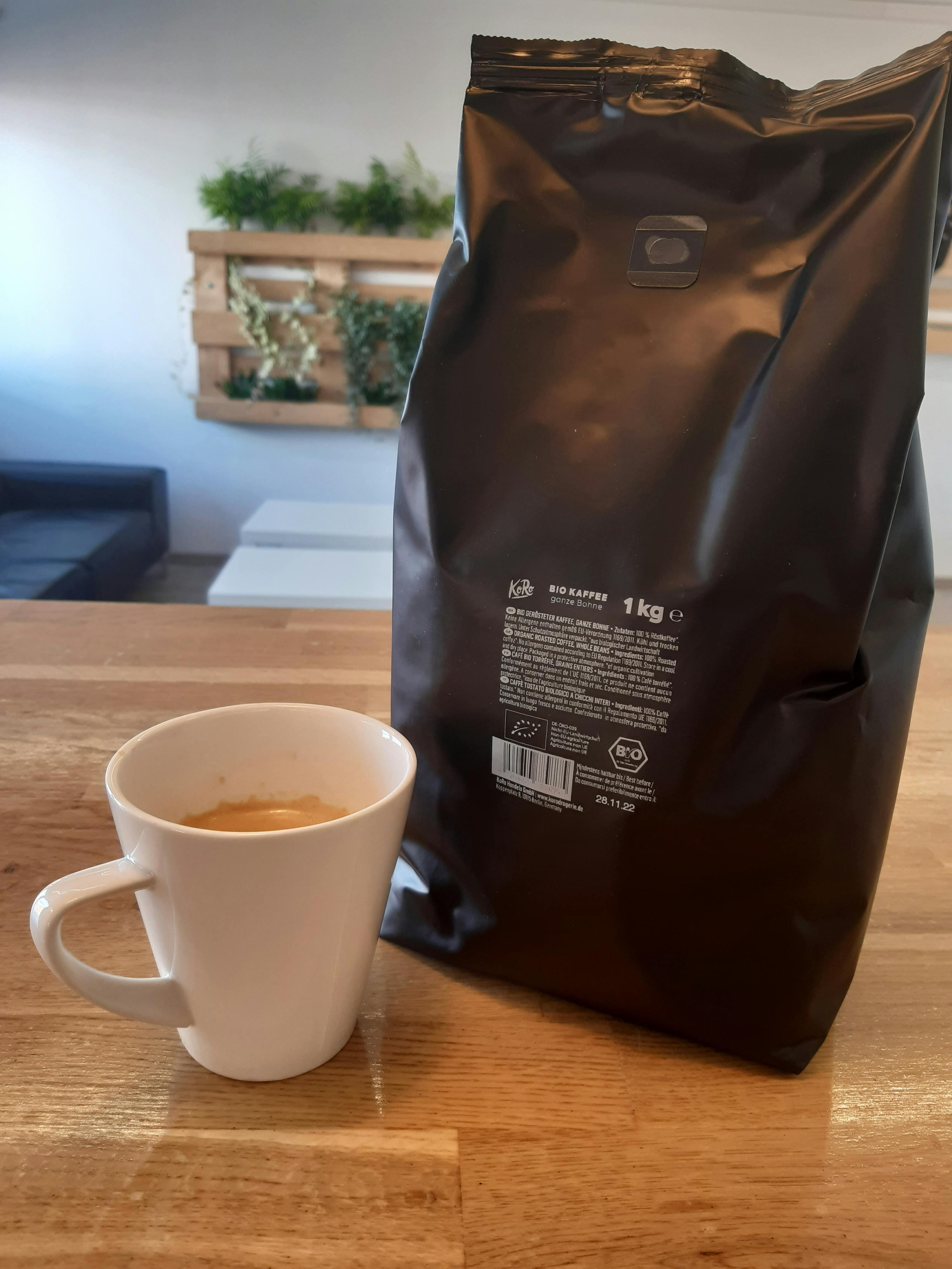eine tasse kaffee steht neben einem sack kaffee auf einem holztisch