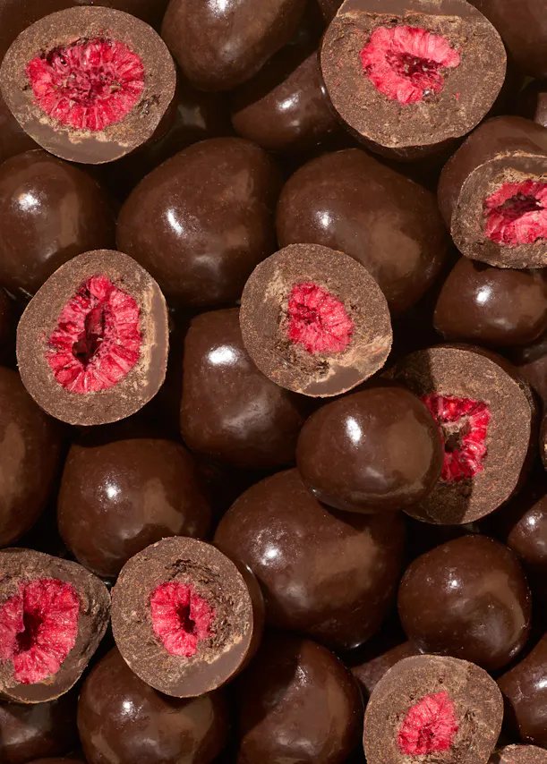 a pile of chocolate covered raspberries that have been cut in half