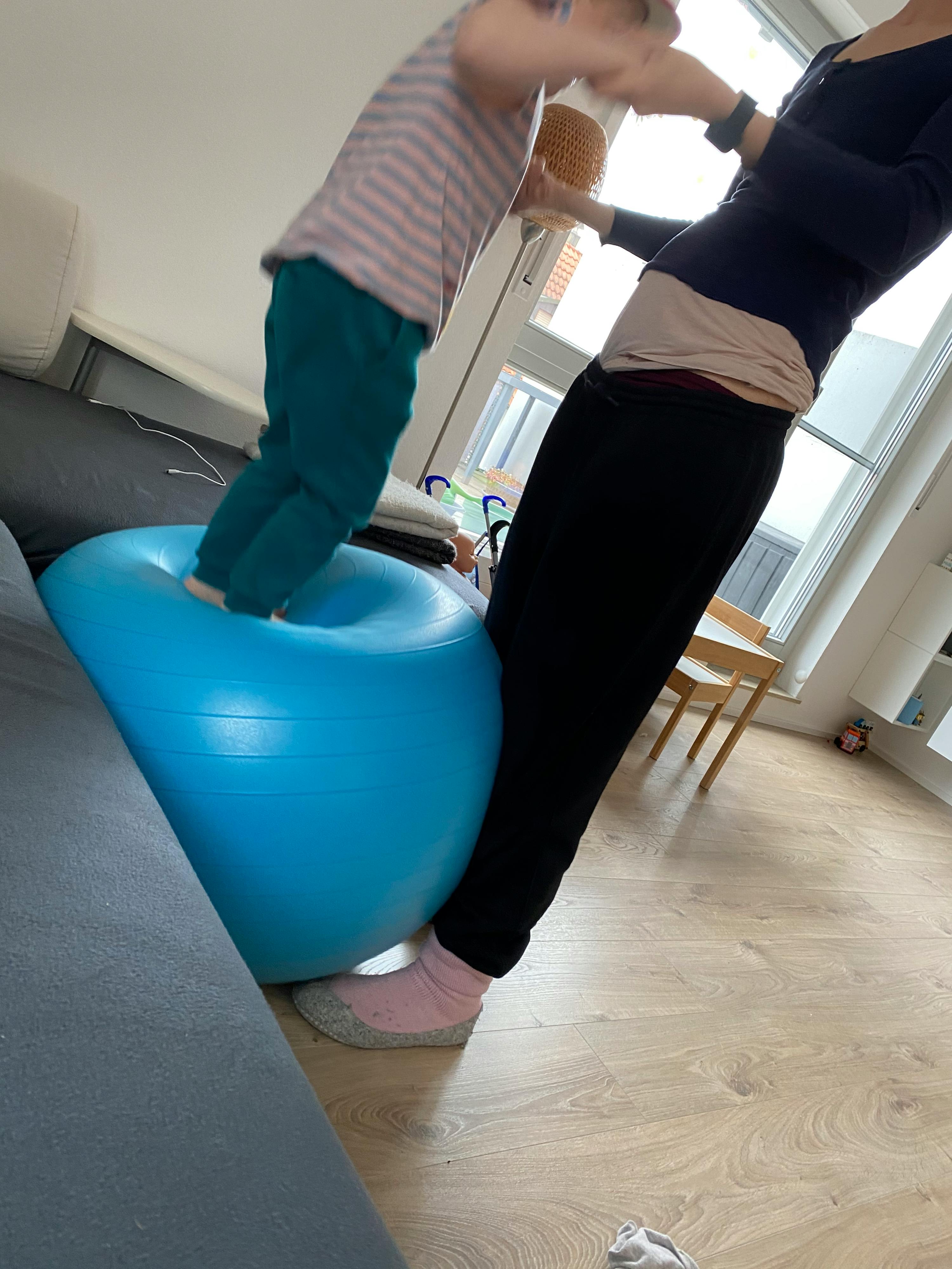 una donna e un bambino giocano con una palla da ginnastica blu