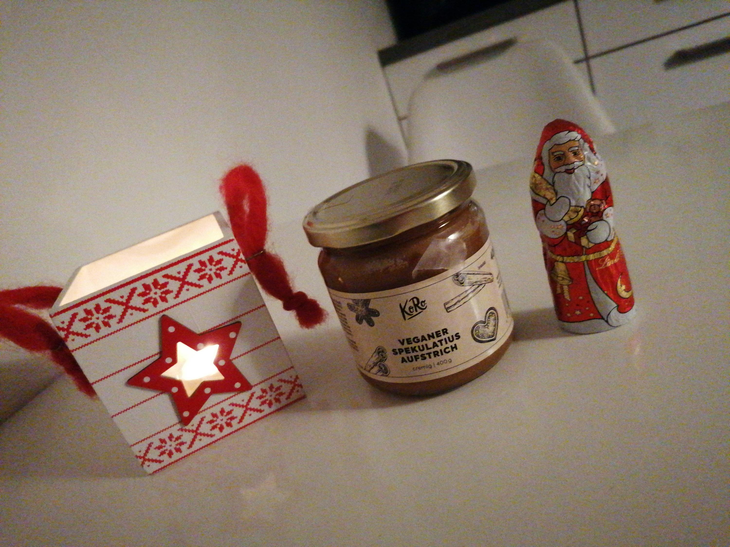 ein weihnachtsmann steht neben einem weihnachtsgeschenk und einem glas kakaoaufstrich