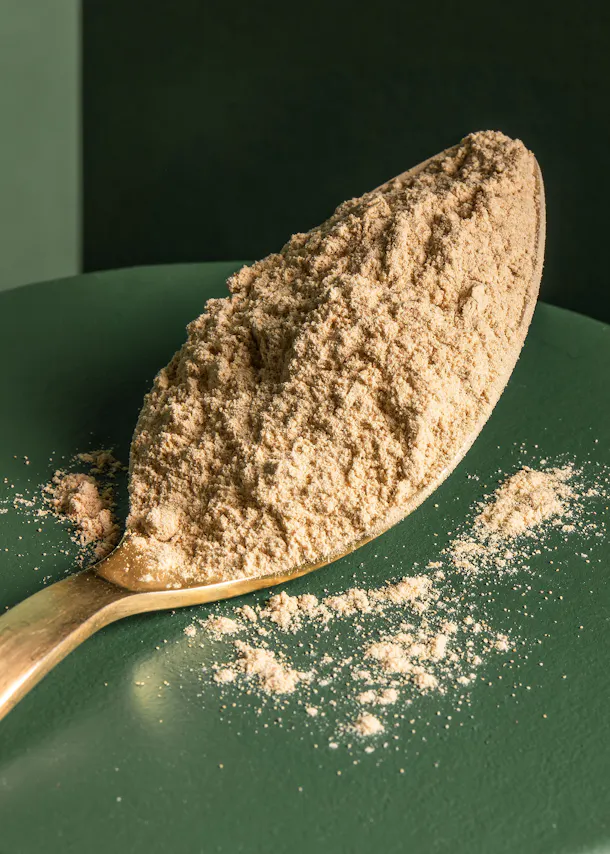une cuillère remplie de poudre est posée sur une table verte