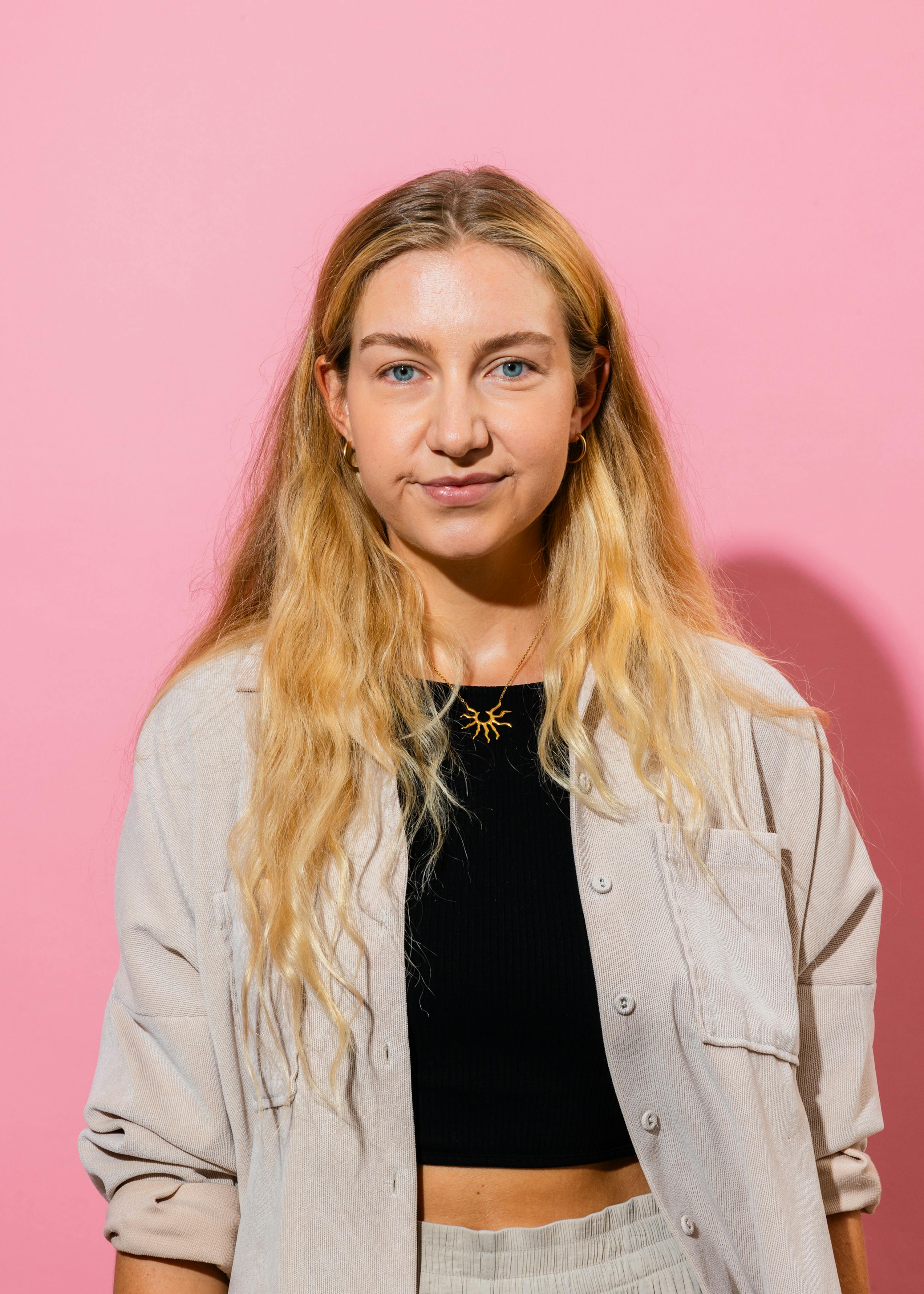 une femme aux cheveux blonds porte une chemise blanche et un haut noir