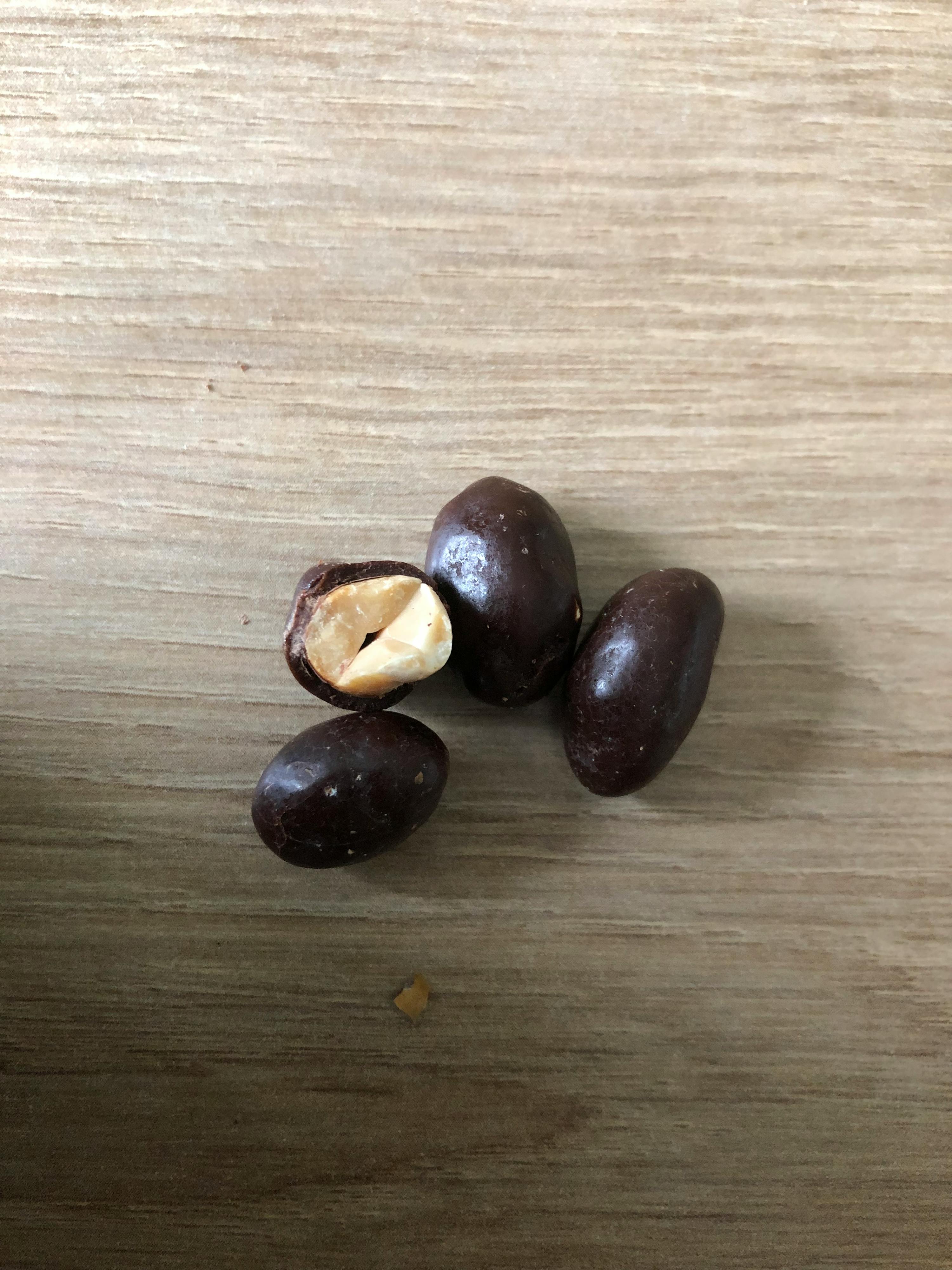 eine Gruppe von Schokoladenbeschichteten Erdnüssen auf einem Holztisch