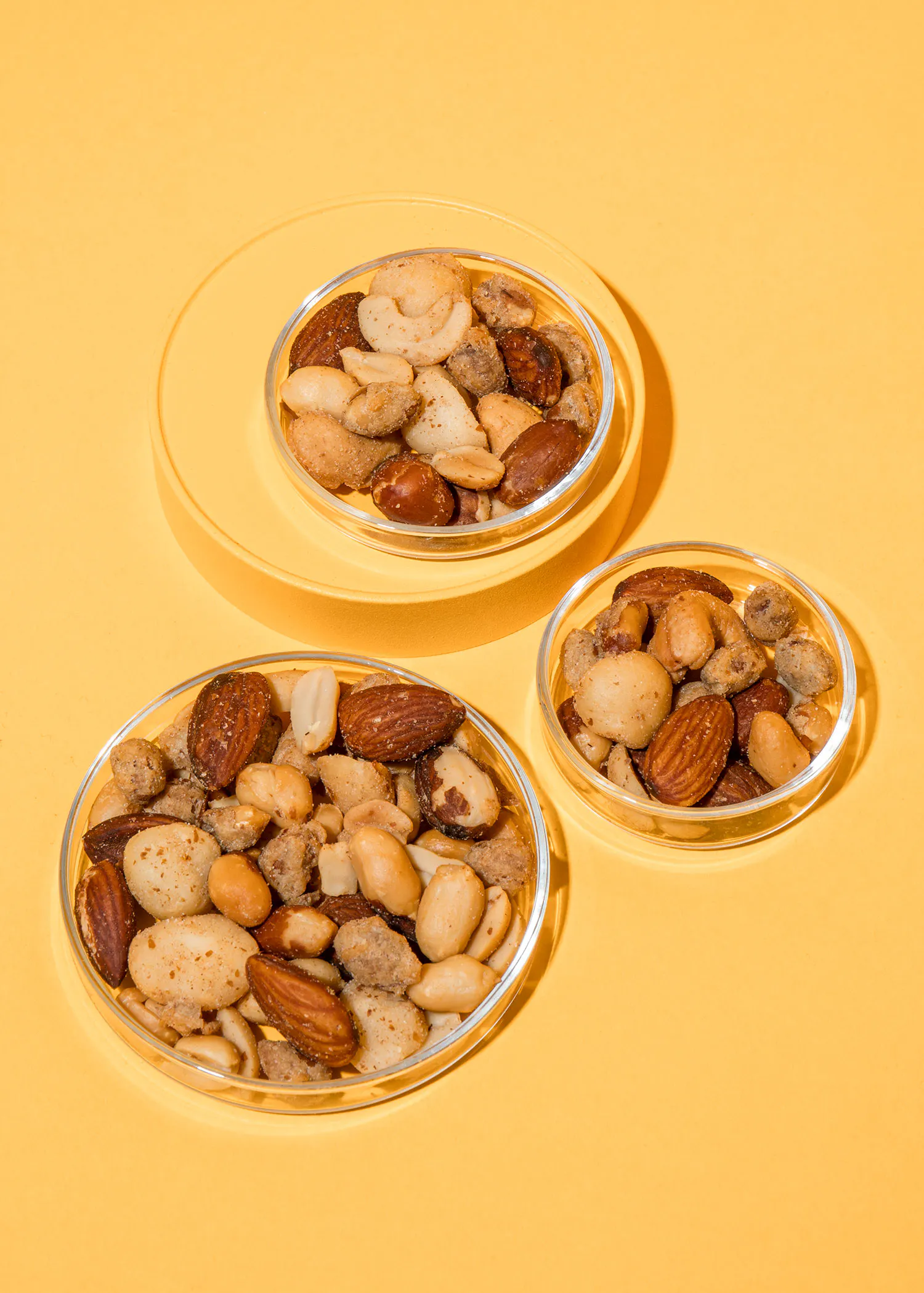 trois bols en verre remplis de noix sur un fond jaune