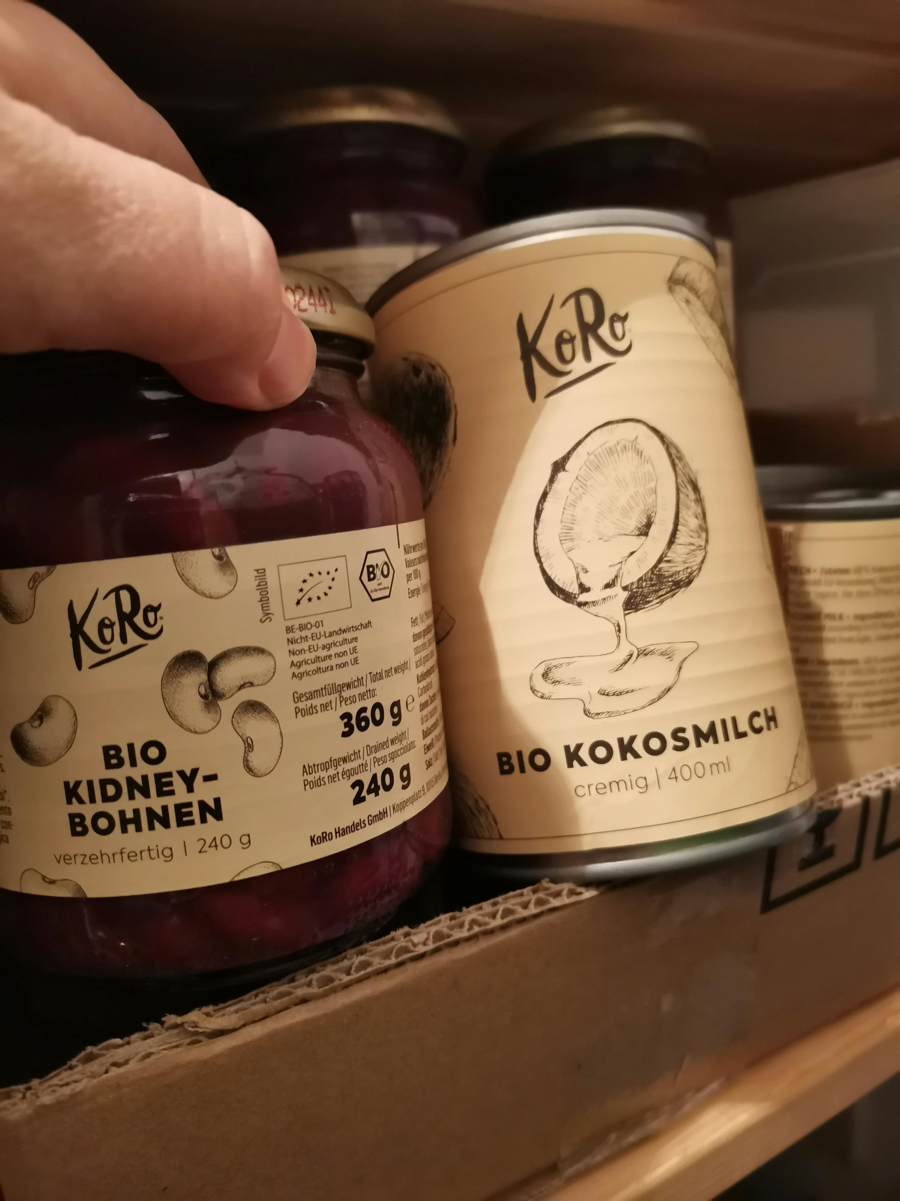 a person is holding a jar of kidney beans next to a can of coconut milk