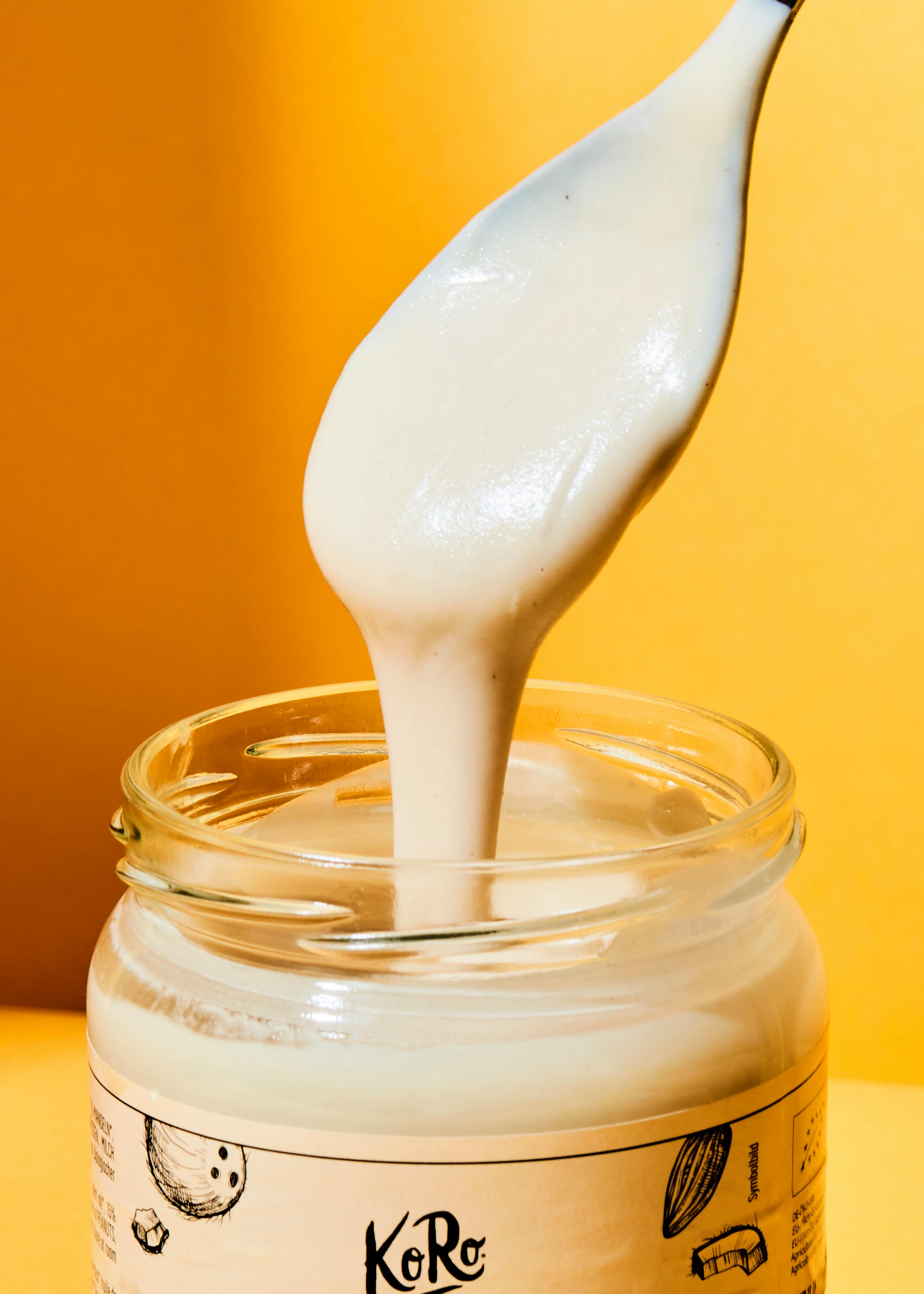 a spoon is pouring white liquid into a jar that says koro
