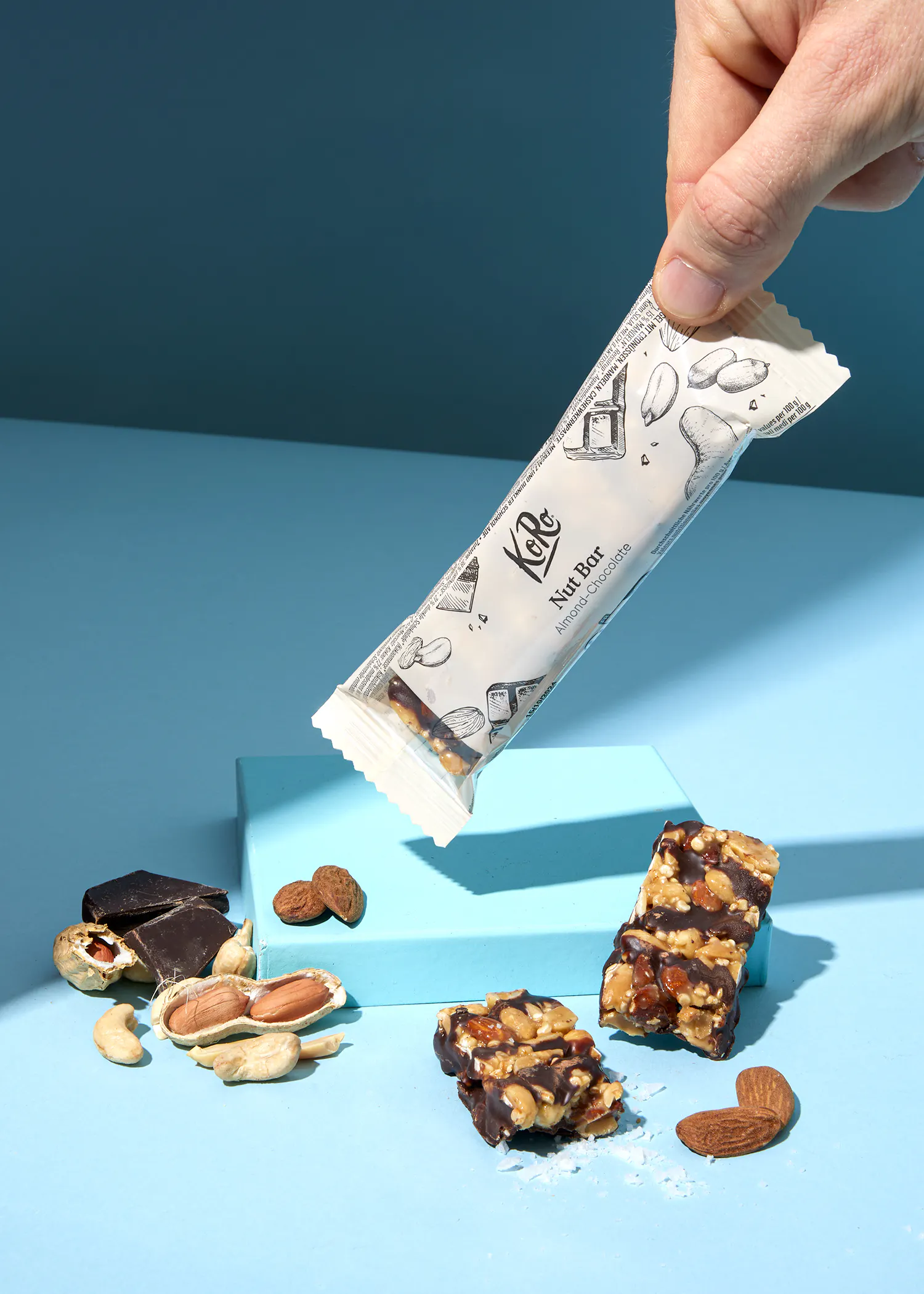 une personne tient une barre de noix kole sur une table bleue