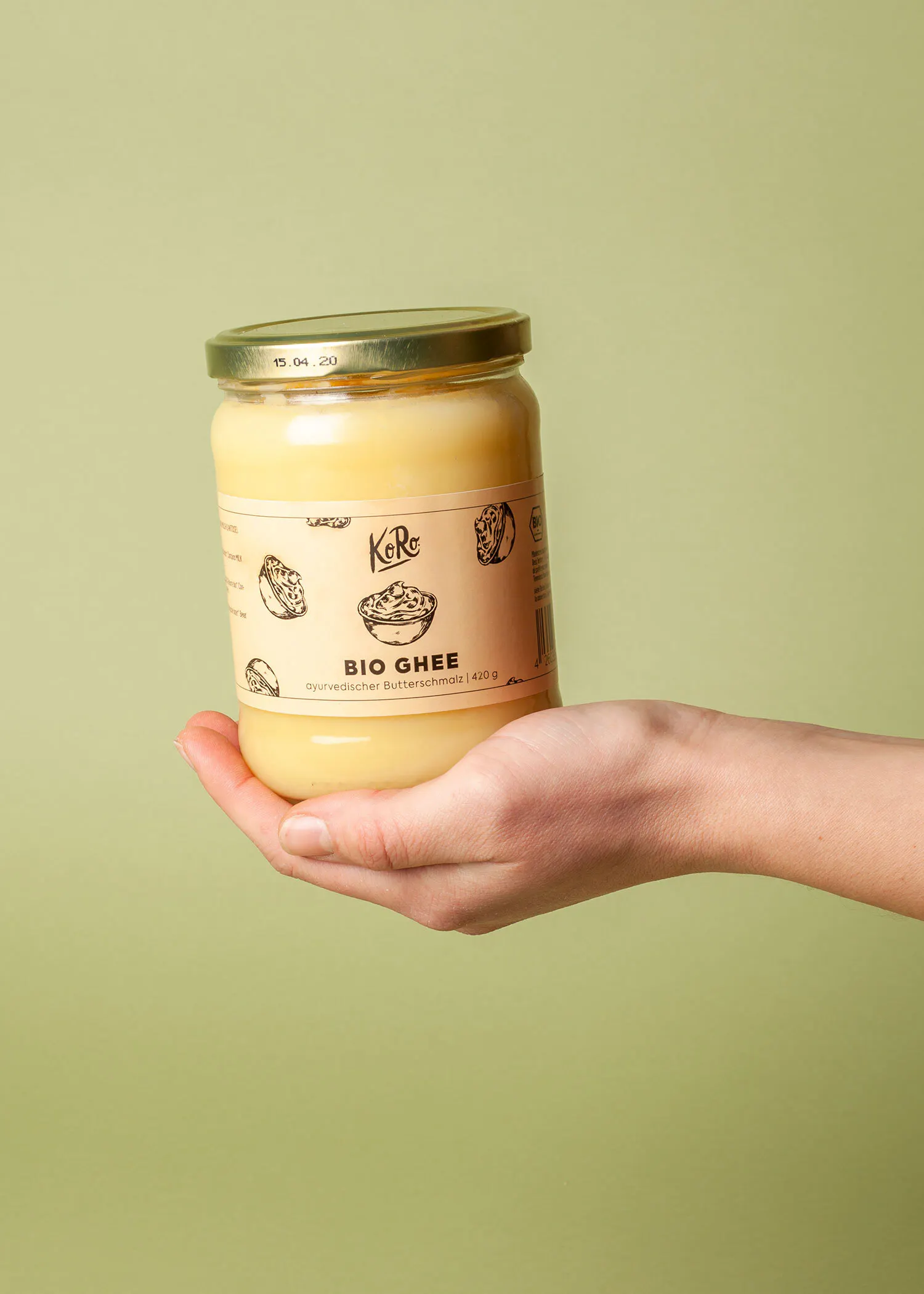 une personne tient un pot de ghee bio à la main