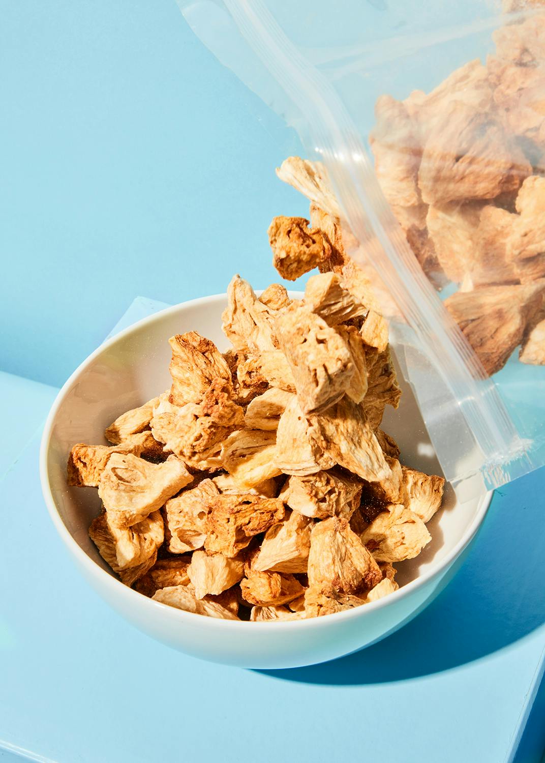 un bol blanc rempli de morceaux de nourriture sur une table bleue