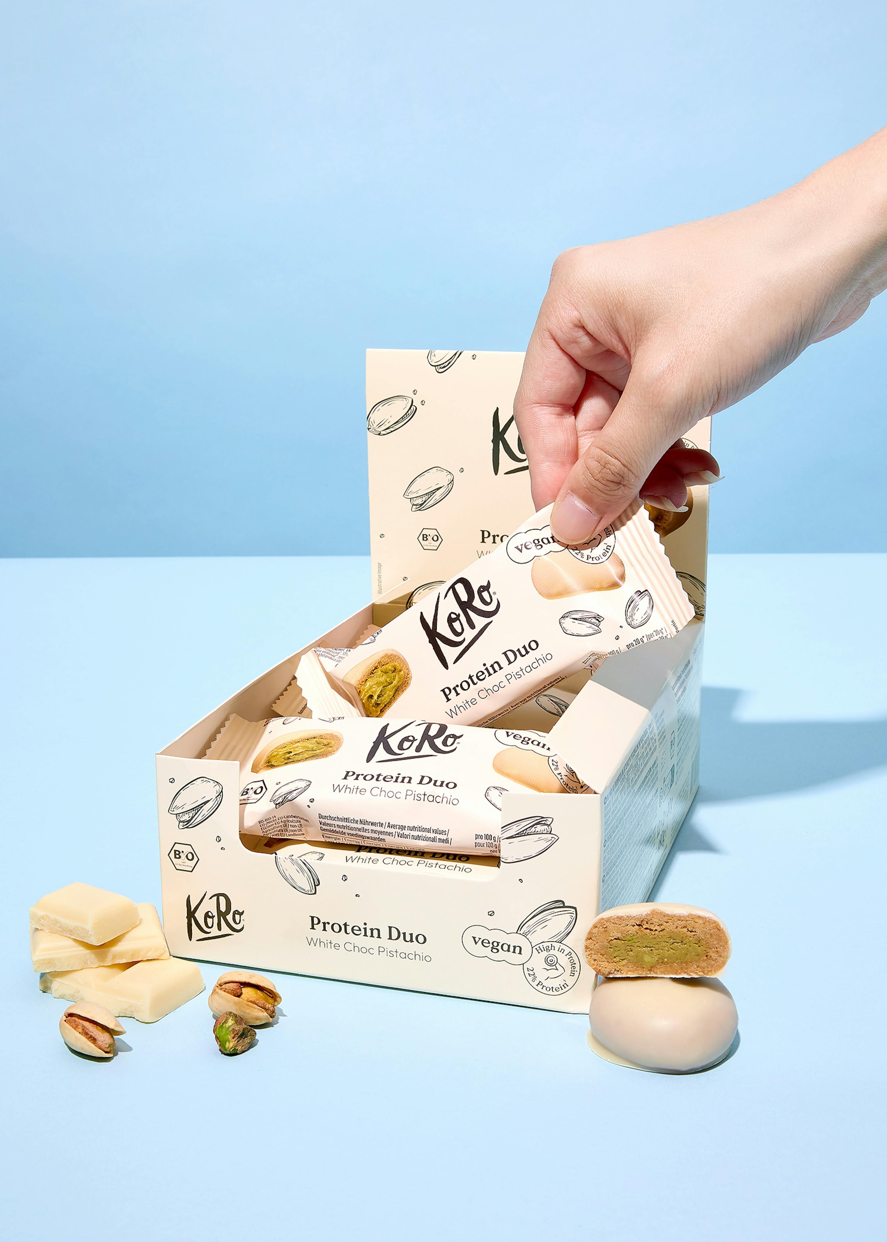 une personne tient une barre de protéines à côté d' une boîte