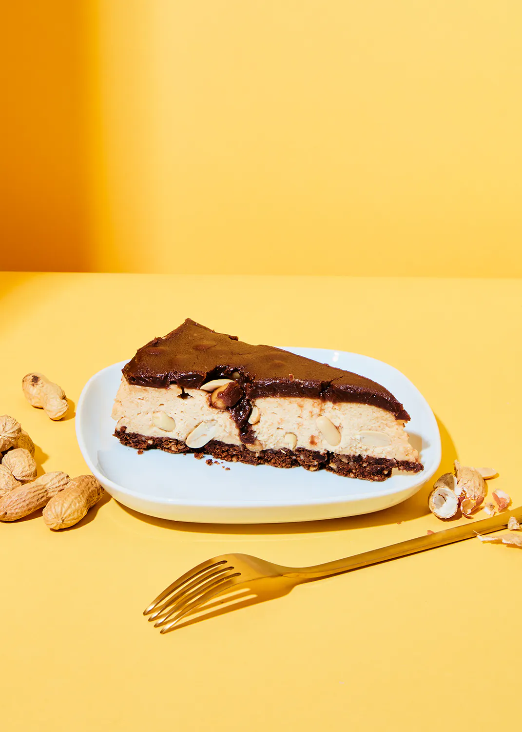 un trozo de pastel de mantequilla de maní está en un plato blanco con un tenedor