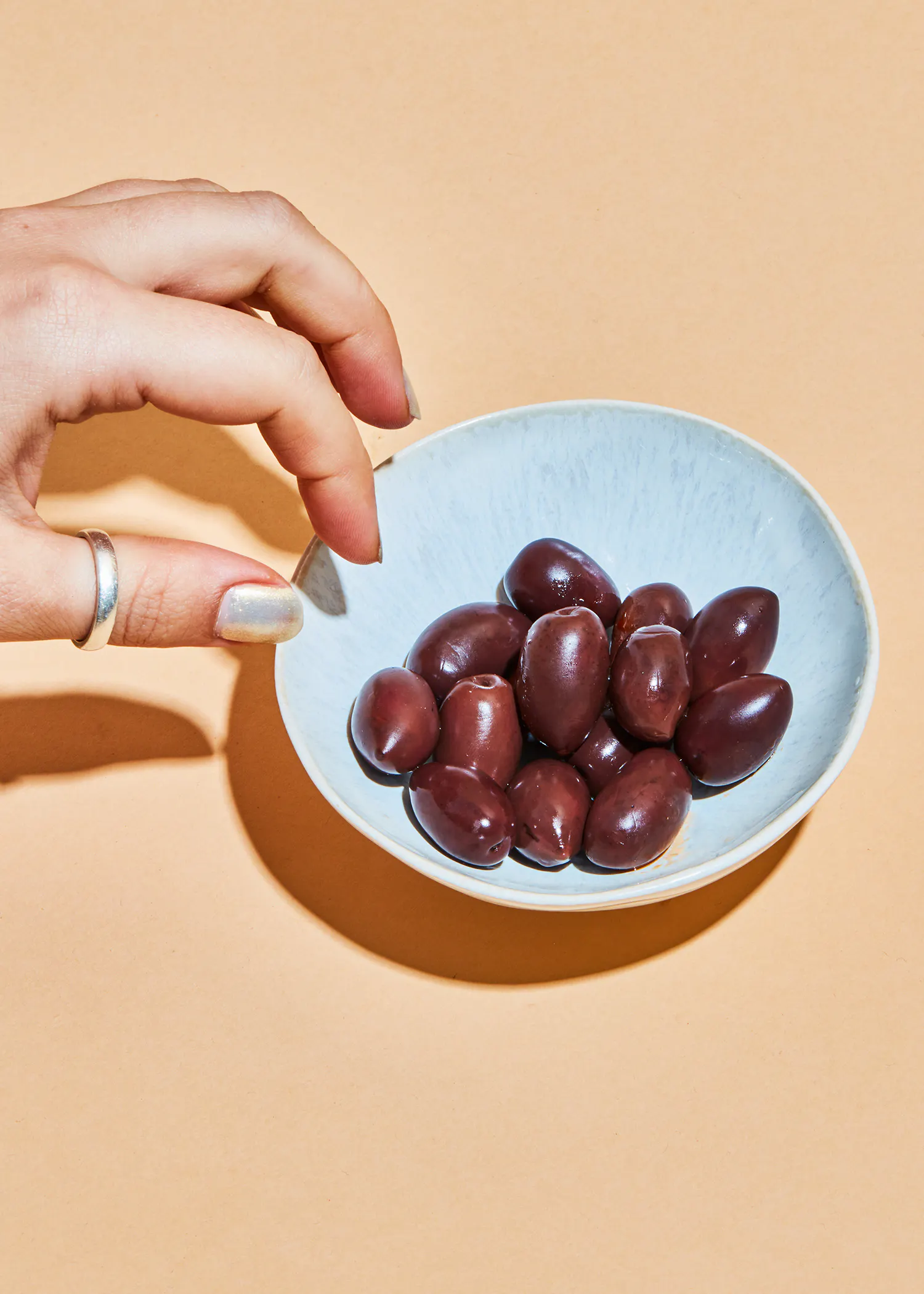 une personne tient un bol bleu rempli d' olives