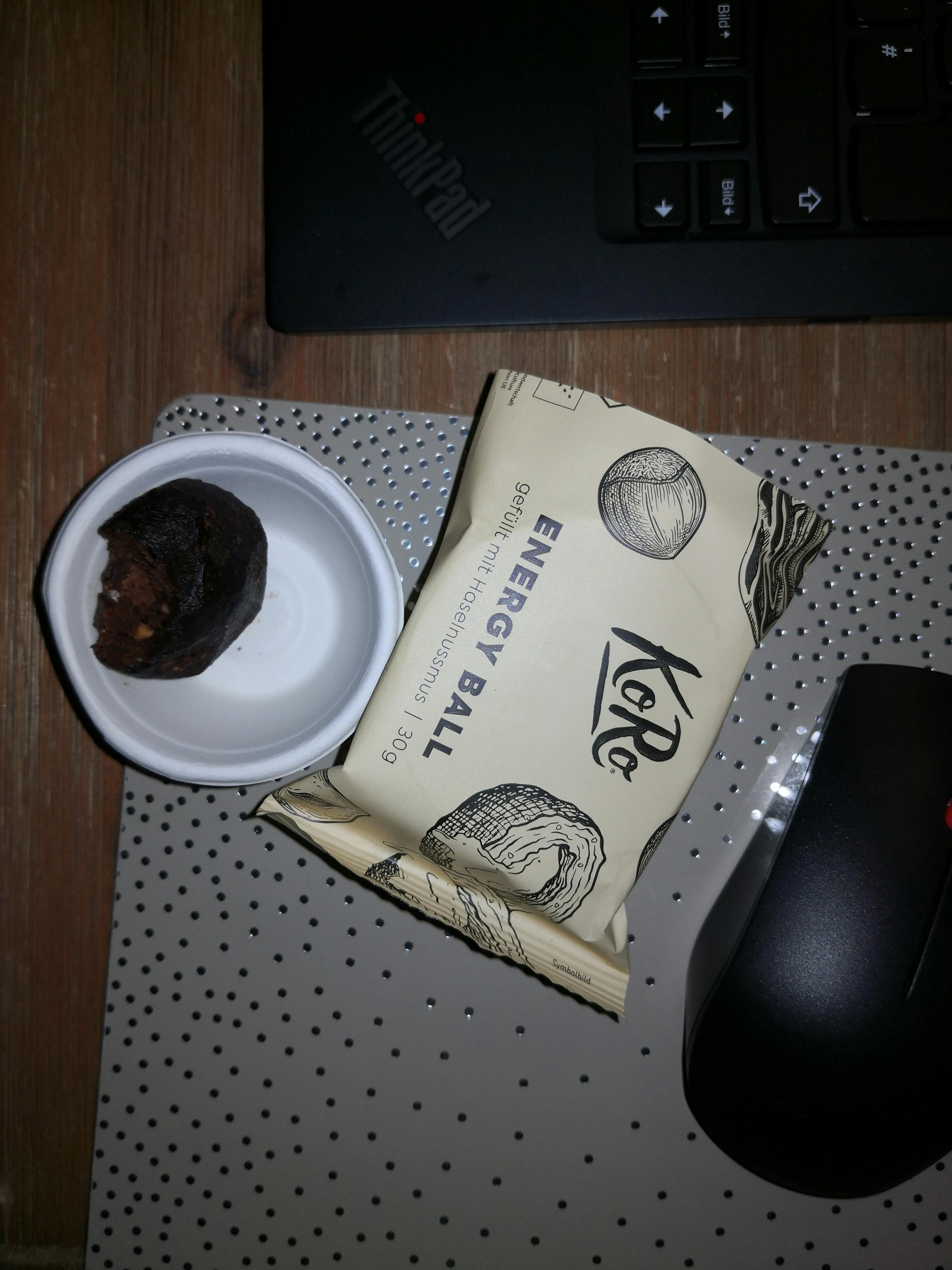 una piccola ciotola e un sacchetto di energy ball sono su un tavolo accanto a un computer portatile