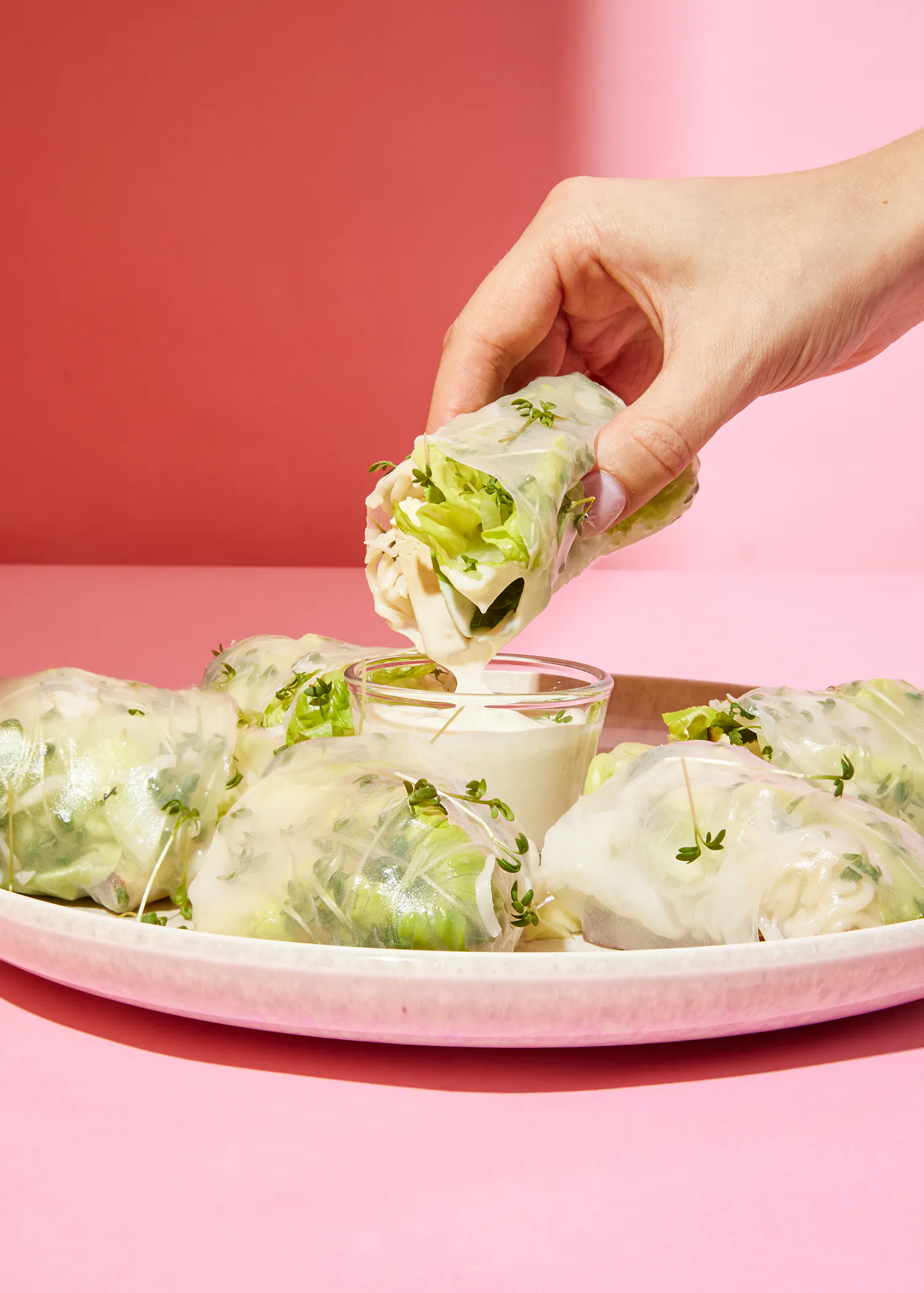 une personne verse une sauce sur un rouleau de laitue
