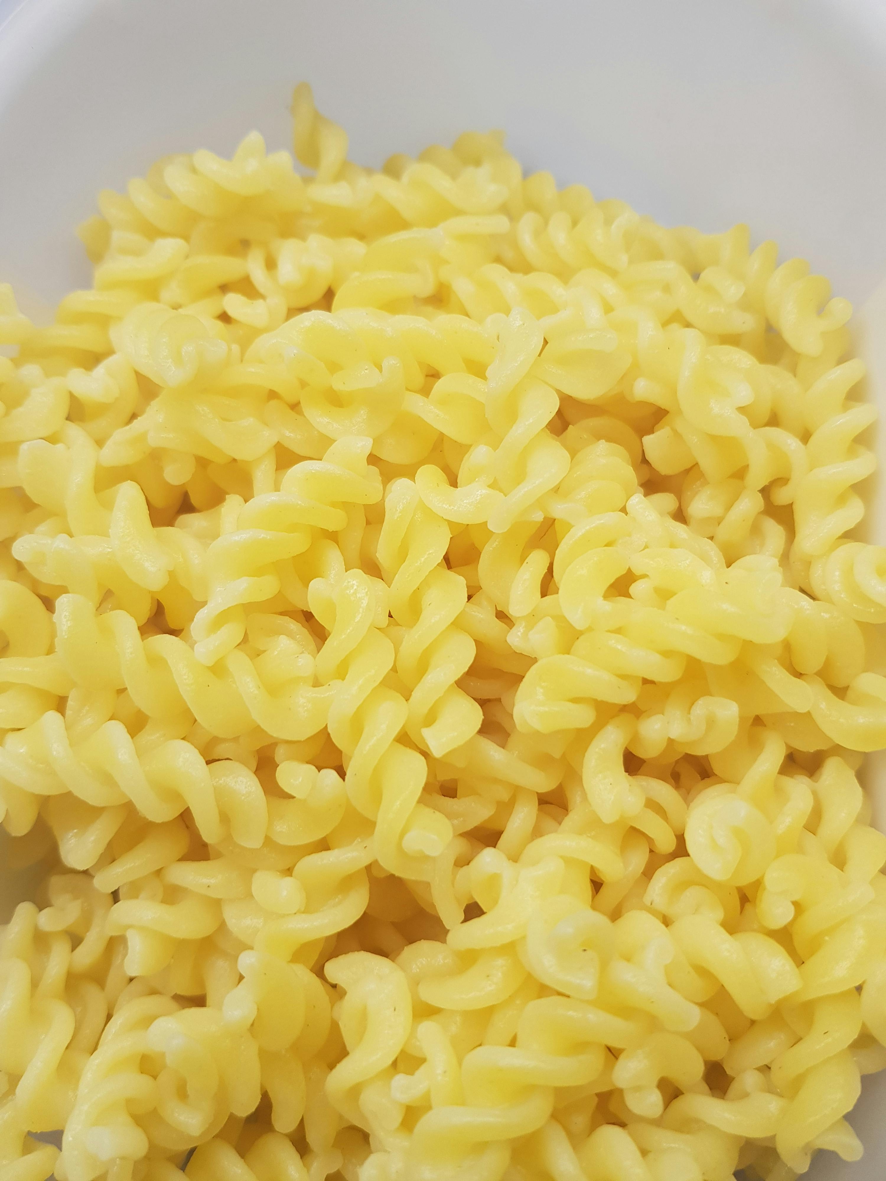 eine weiße Schüssel mit gelben Nudeln in spiralenform