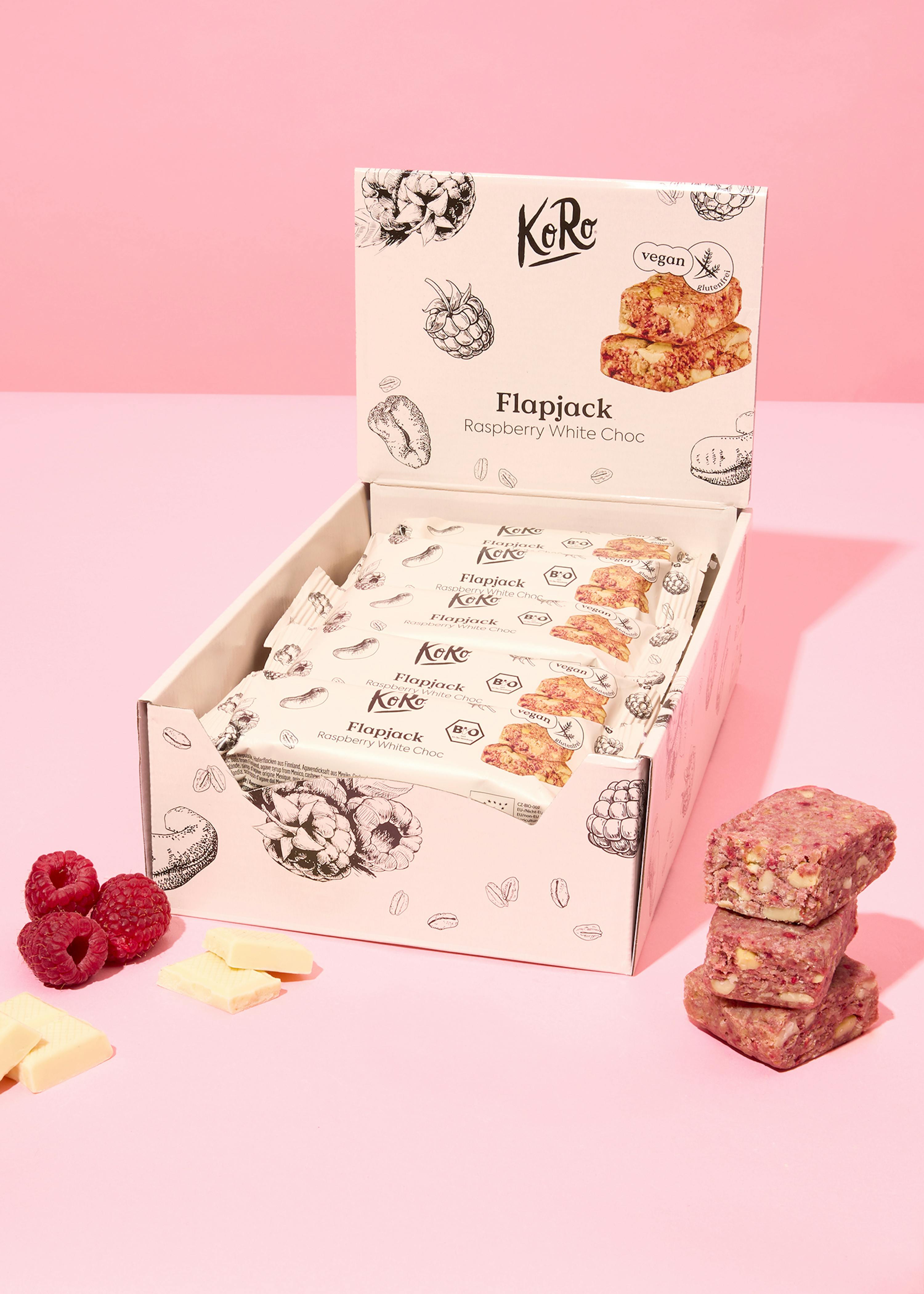 une boîte de flapjack framboise et chocolat blanc sur fond rose