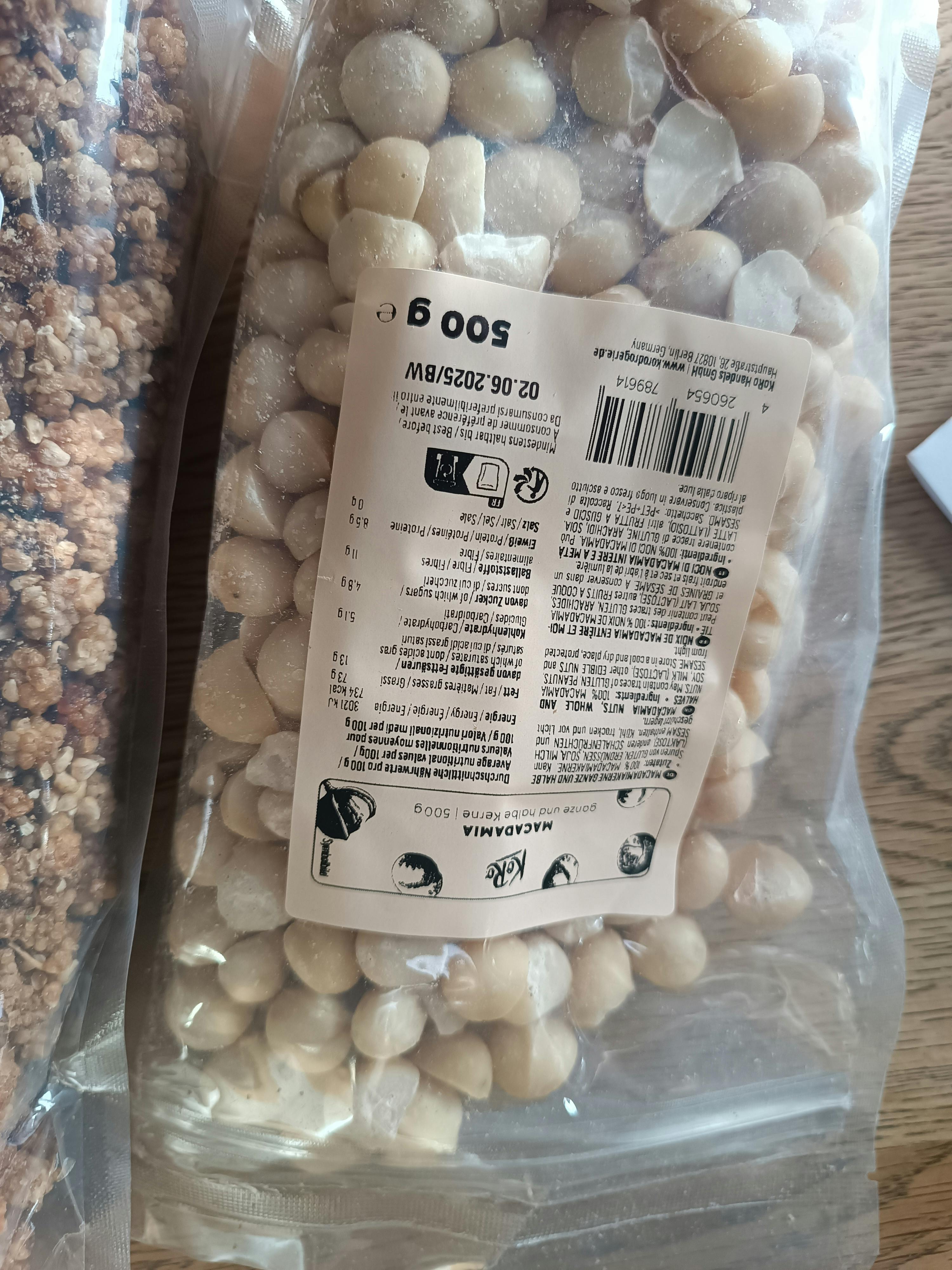 un sacchetto di macadamia è seduto su un tavolo di legno accanto a un sacchetto di granola