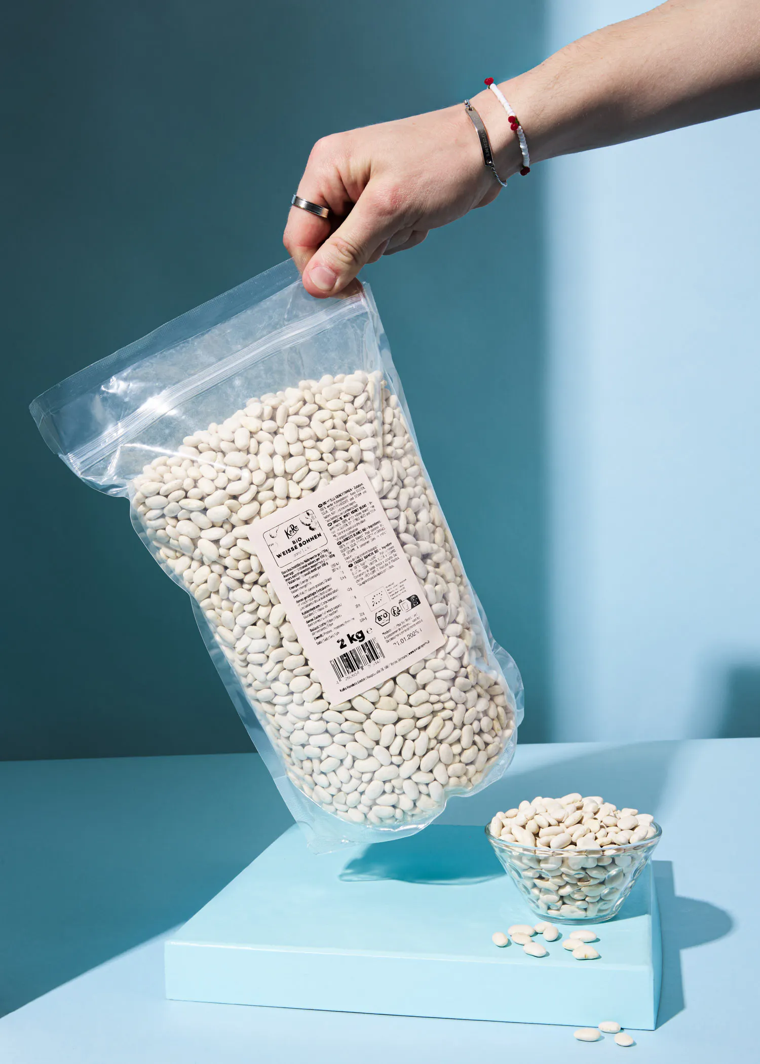 a person is holding a bag of white beans on a blue surface