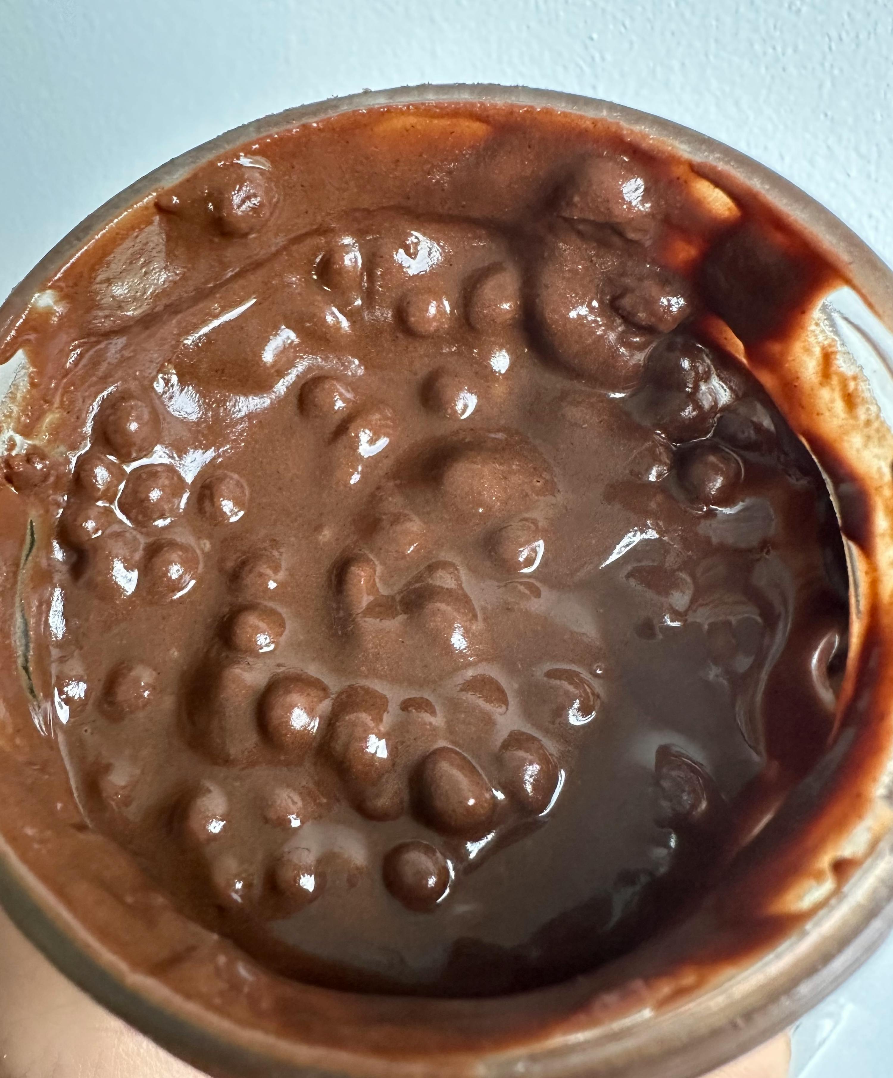 una persona tiene in mano un barattolo di pudding al cioccolato con gocce di cioccolato