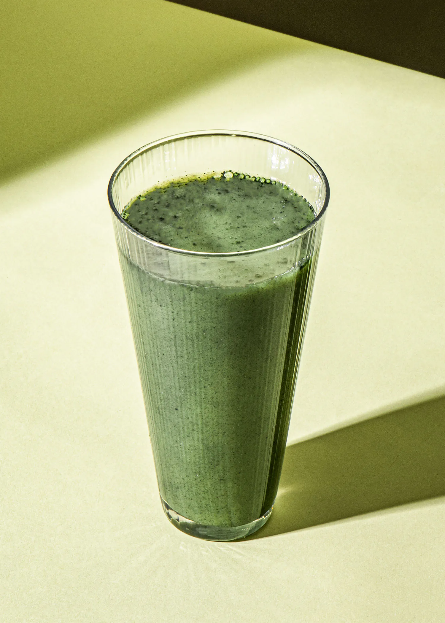 un verre rempli d' un smoothie vert est assis sur une table
