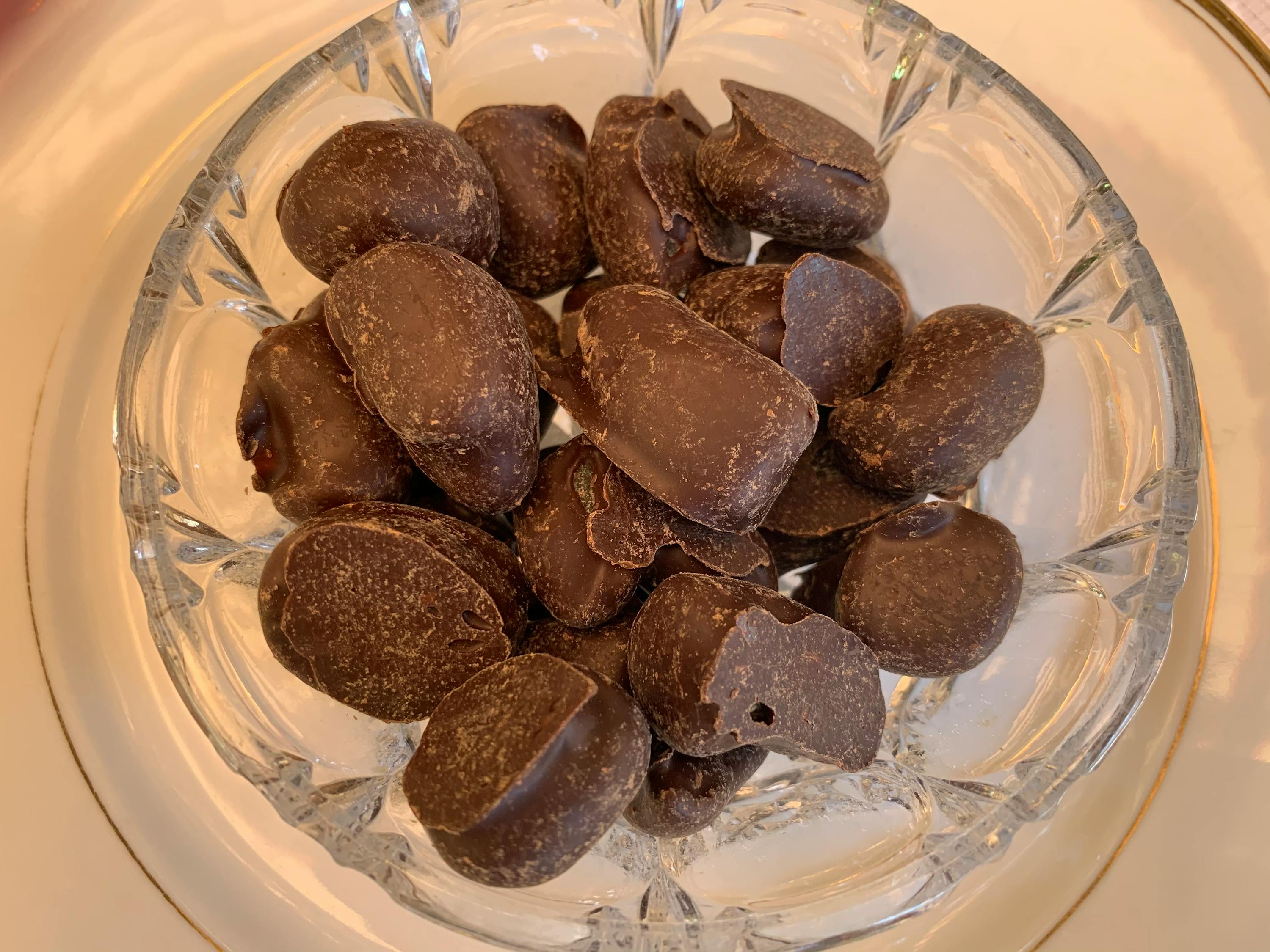 a glass bowl filled with dark chocolate covered almonds