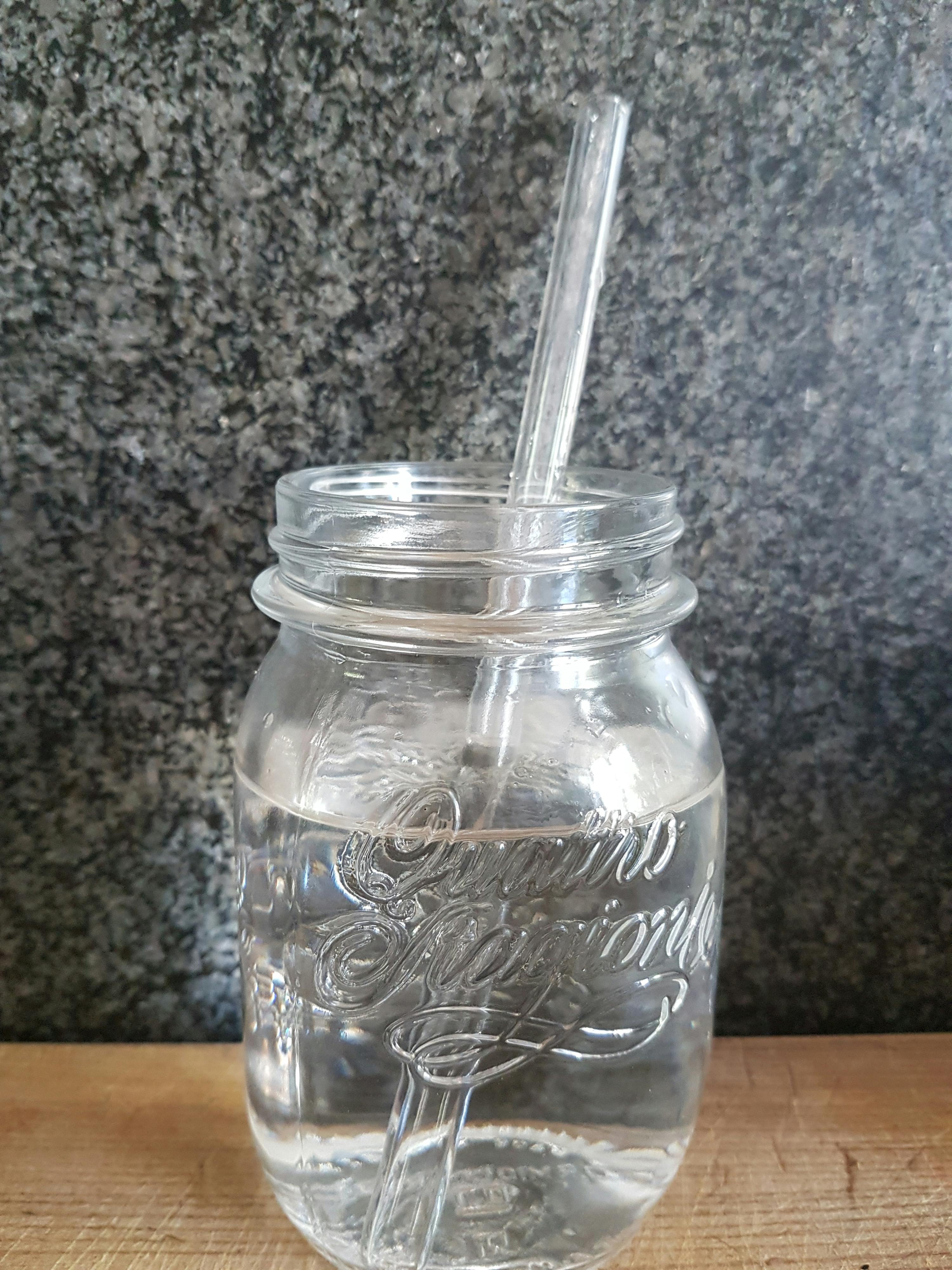 ein Glasgefäß mit einem Strohhalm und der Aufschrift " coca cola " darauf