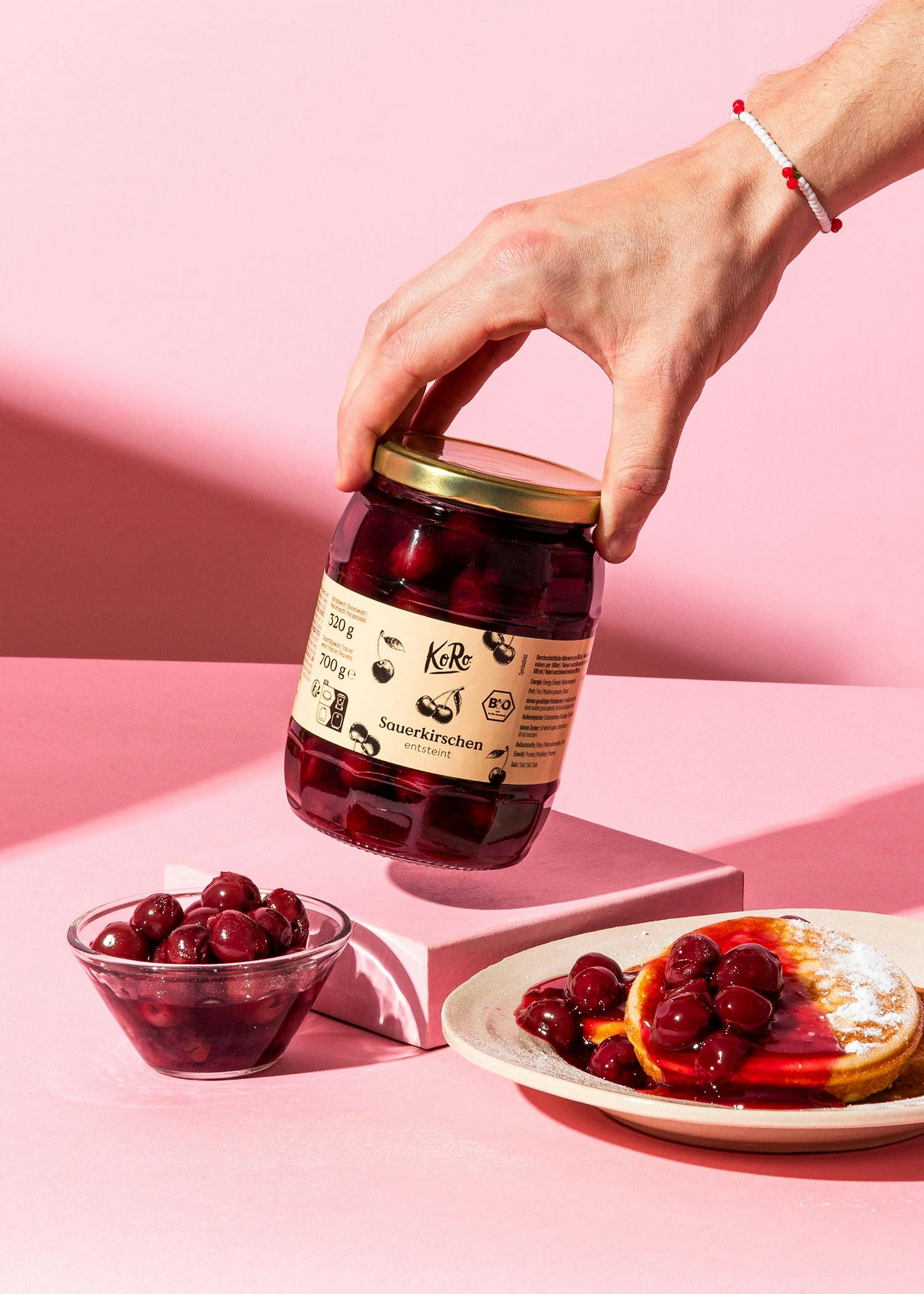 a person is holding a jar of sourkirschen