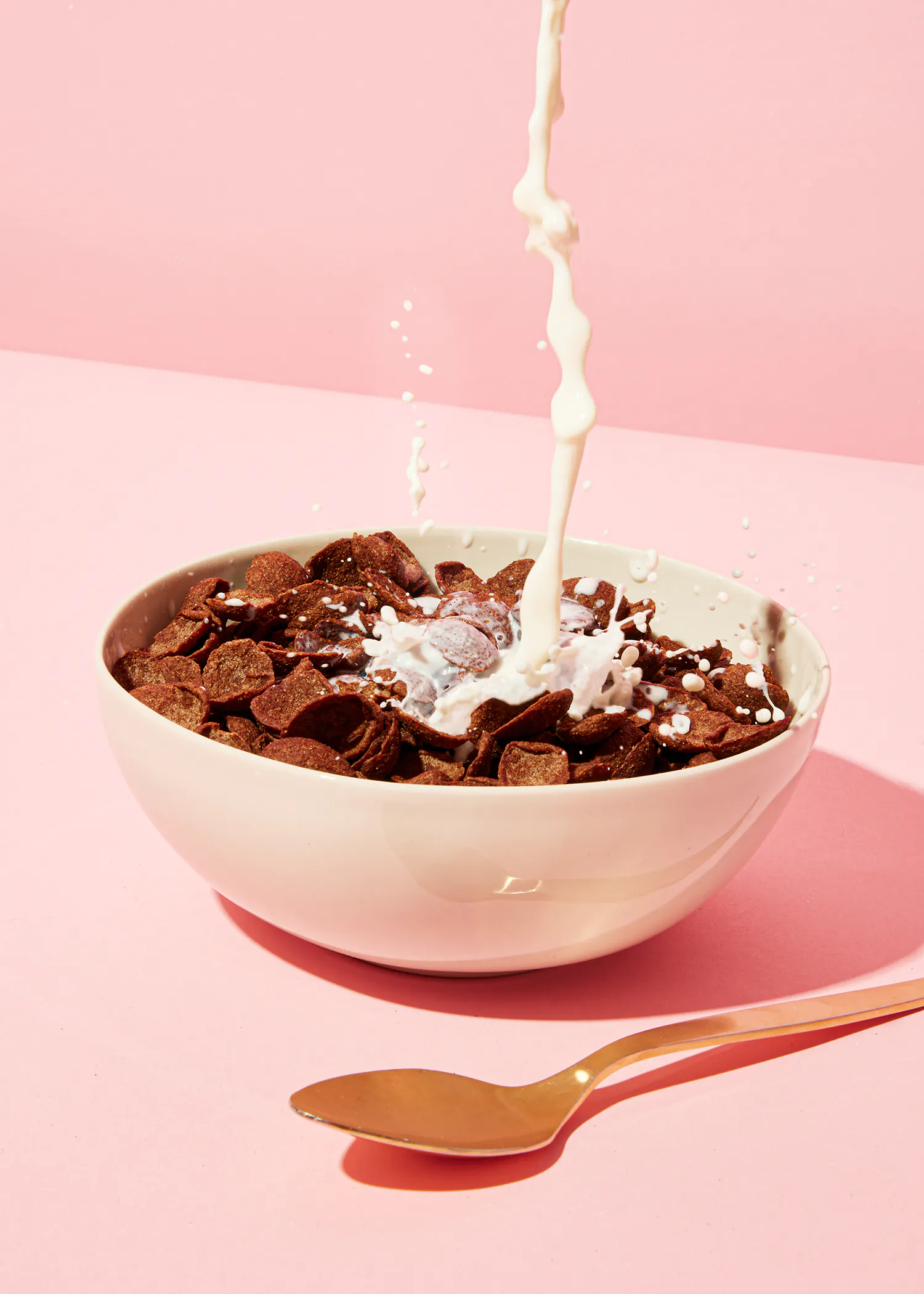 le lait est versé dans un bol de céréales au chocolat avec une cuillère