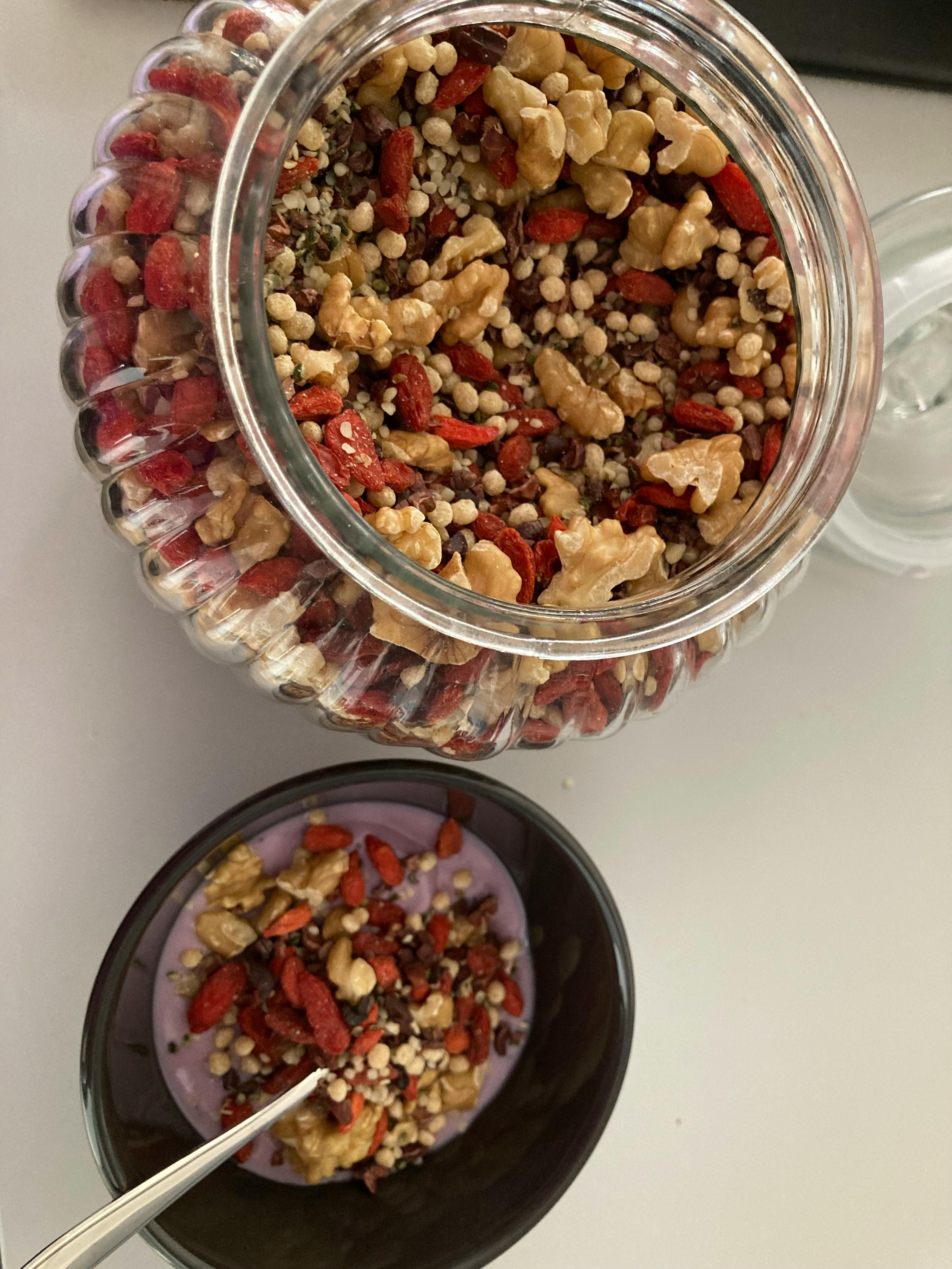 a jar of nuts next to a bowl of yogurt