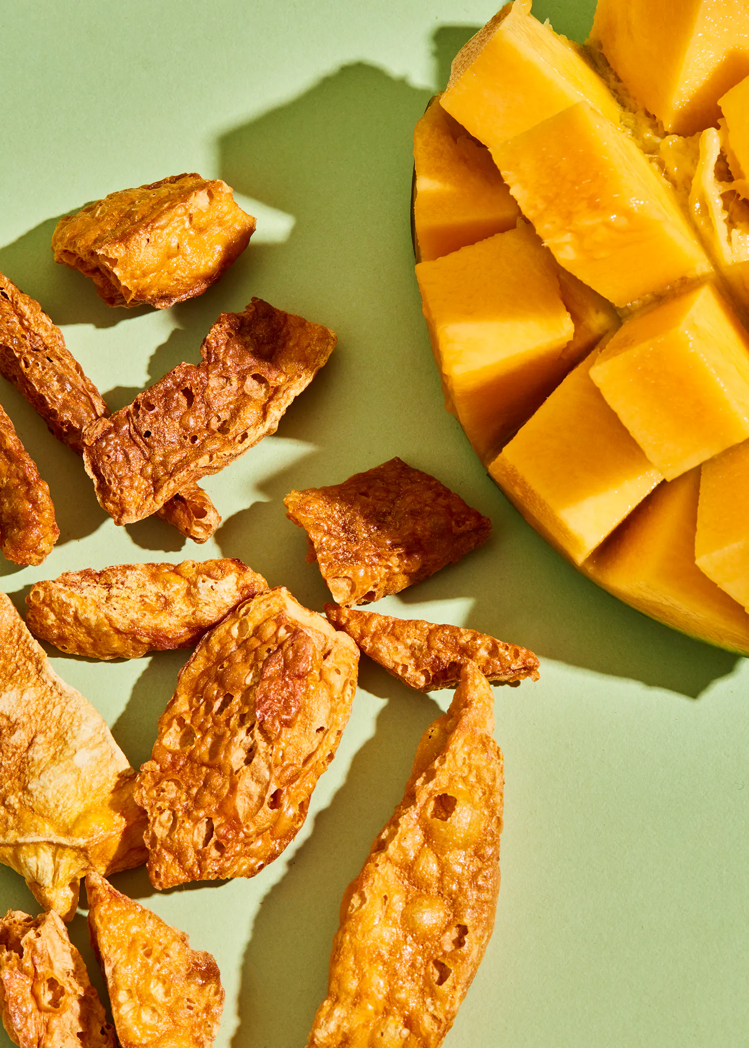 a slice of mango next to a pile of chips