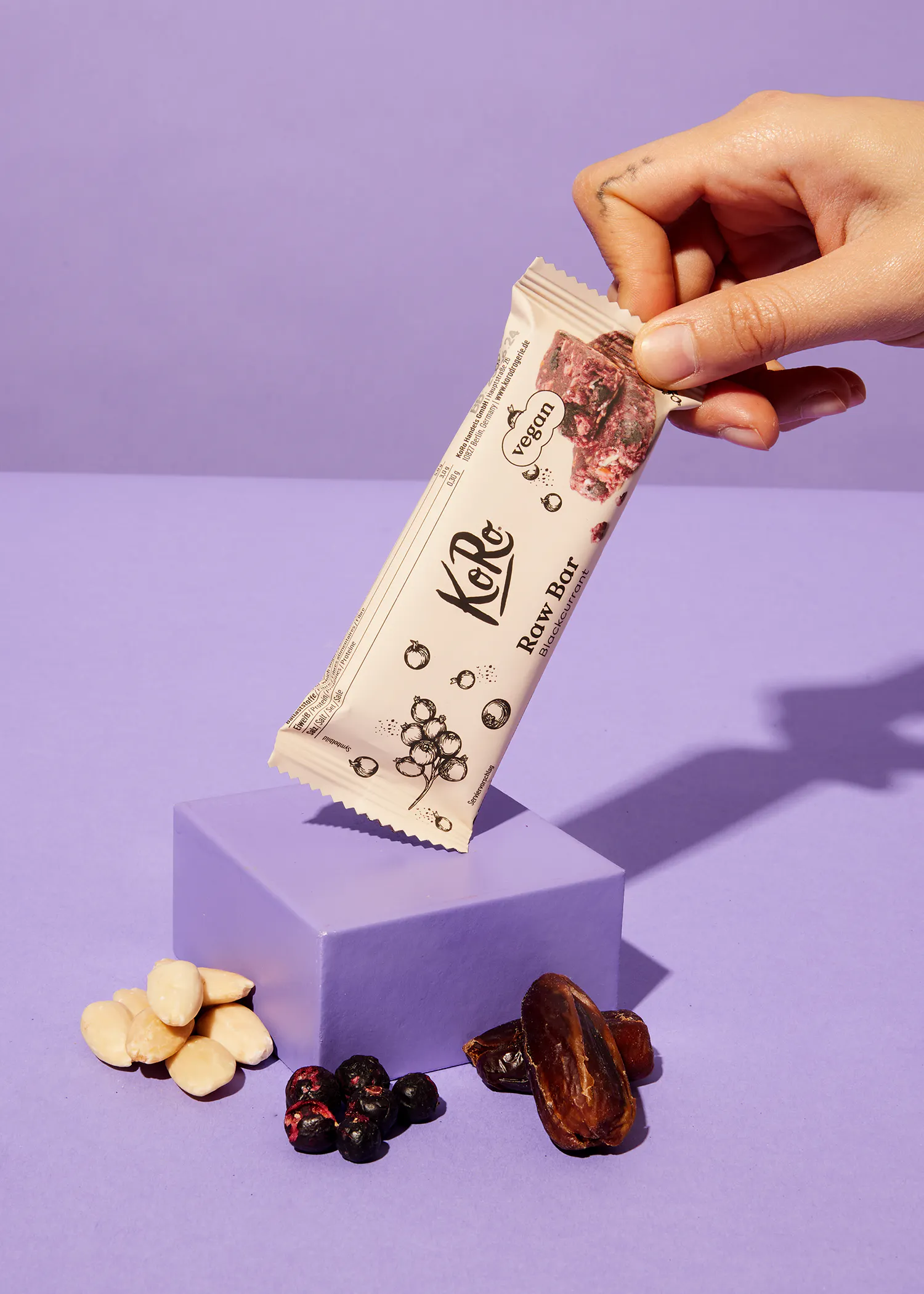 une personne tient une barre de céréales avec des baies et des noix