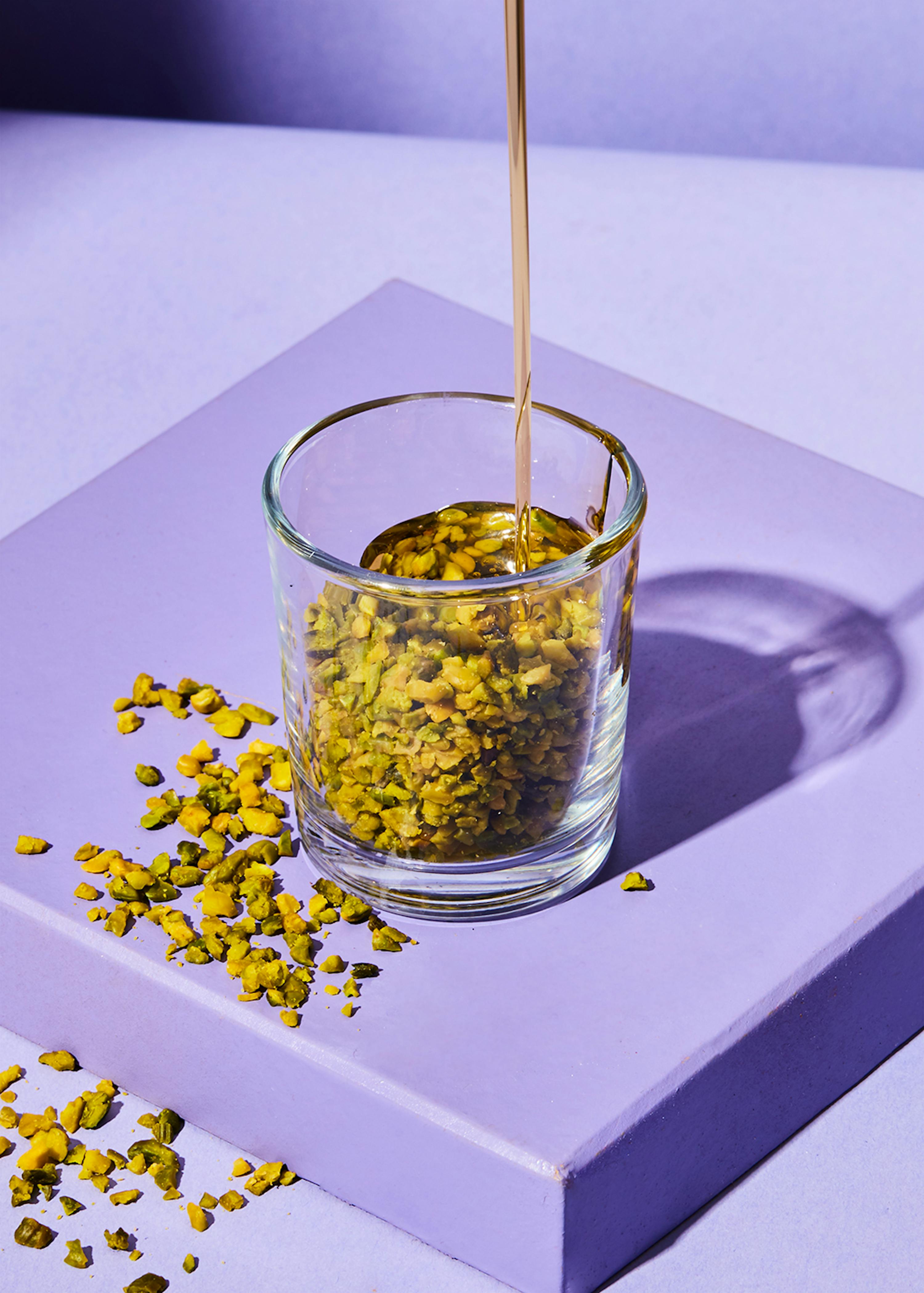 Honig wird in ein Glas gegossen , das mit pistazien gefüllt ist