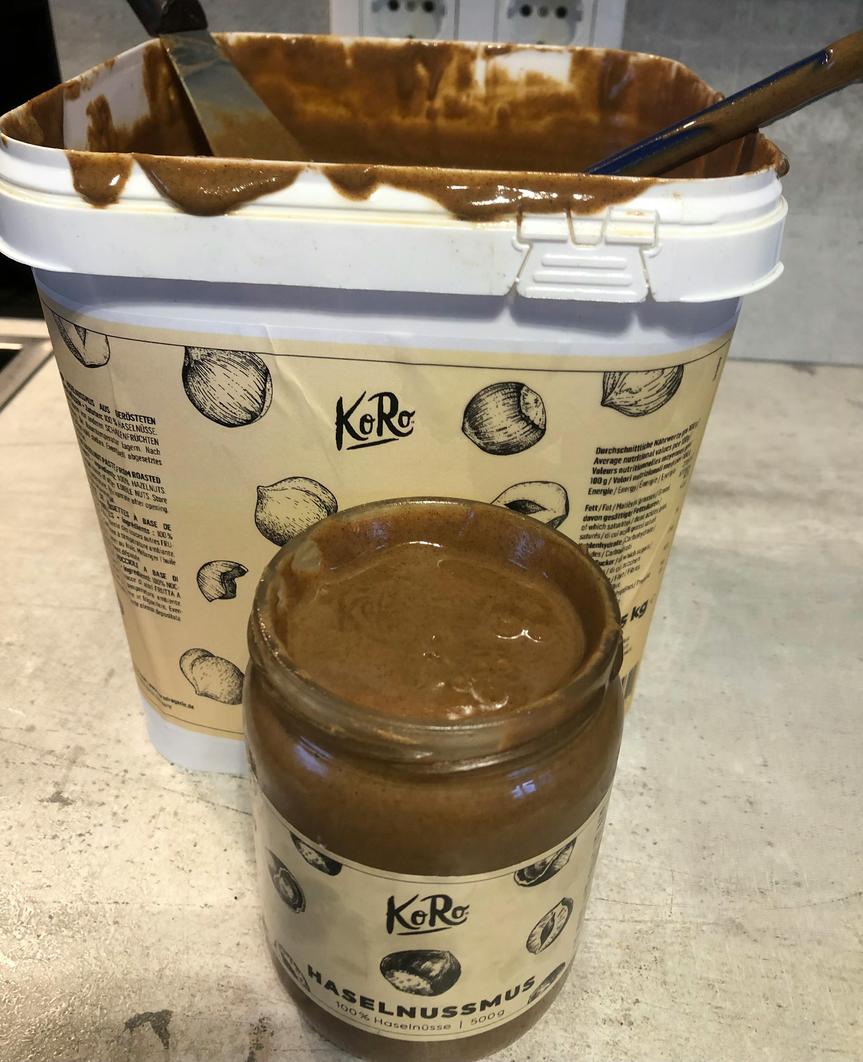 ein Eimer haselnussmus steht neben einem Glas mit haselnussmus