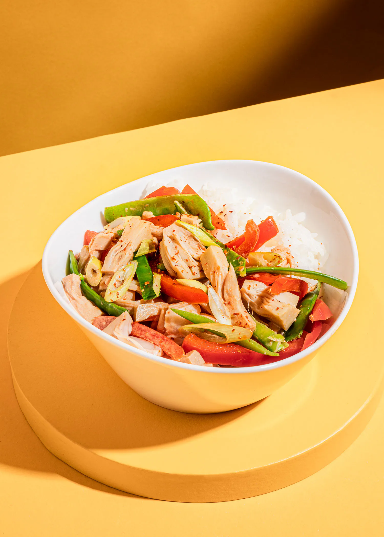 a white bowl filled with meat and vegetables on a yellow surface
