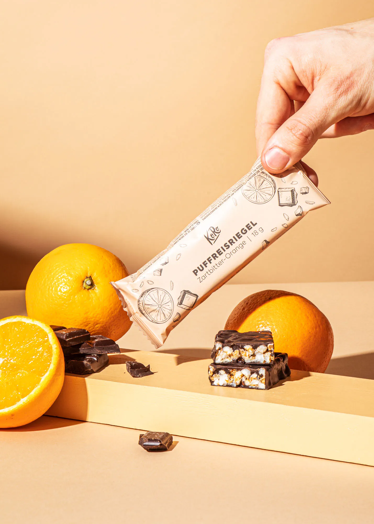 une personne tient une barre de chocolat à côté d' oranges et de noix de coco