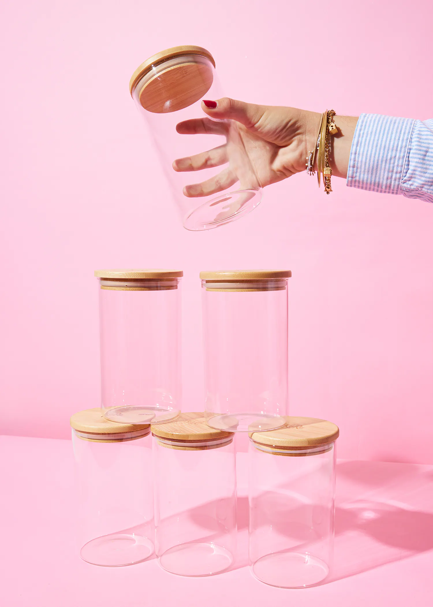 a woman is holding a glass jar with a wooden lid