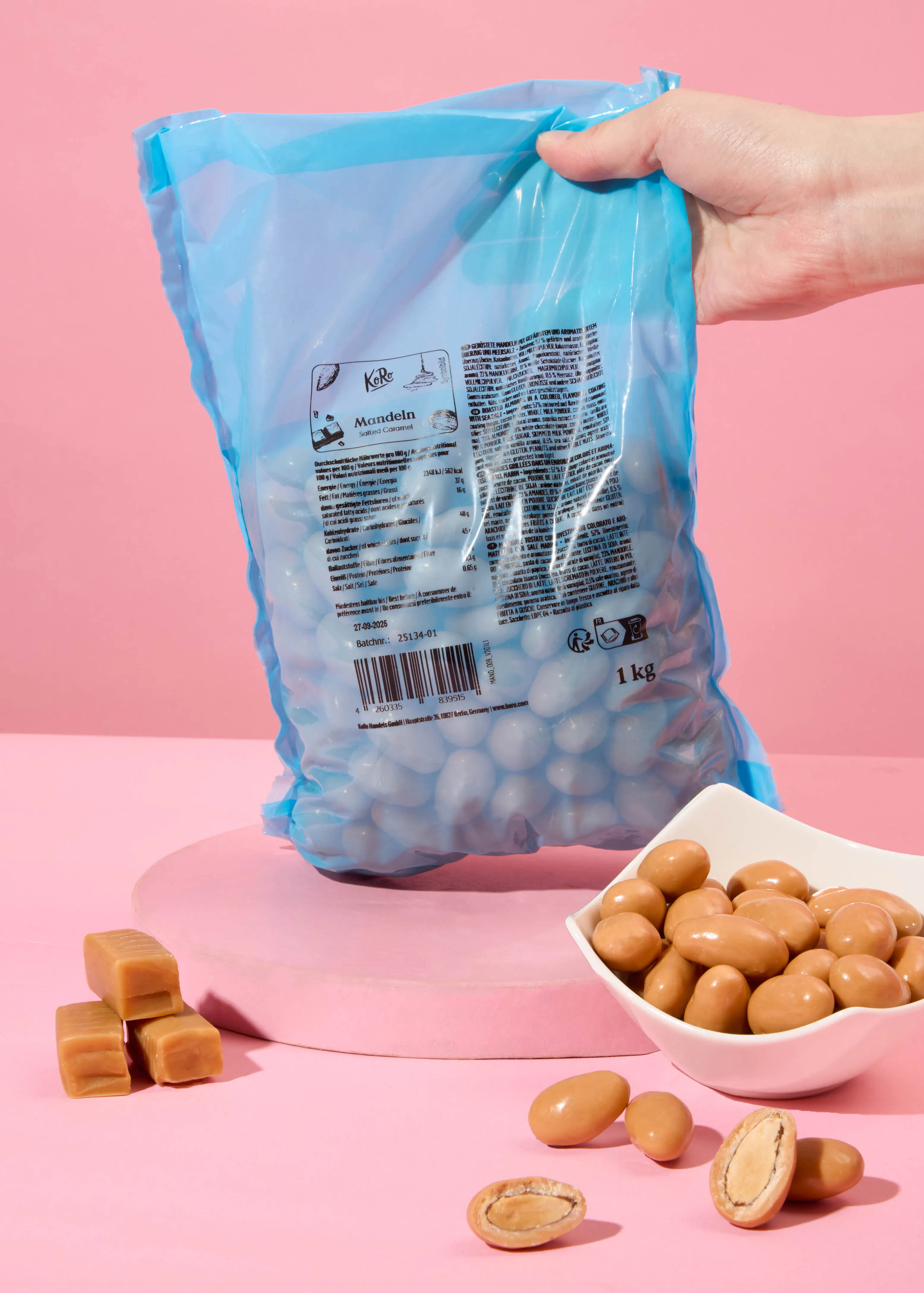 une personne tient un sac d' amandes au caramel à côté d' un bol d' amandes