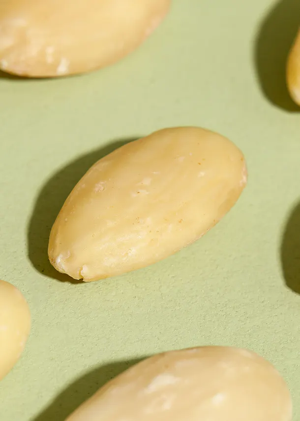 un gros plan d' une amande blanche sur une surface verte