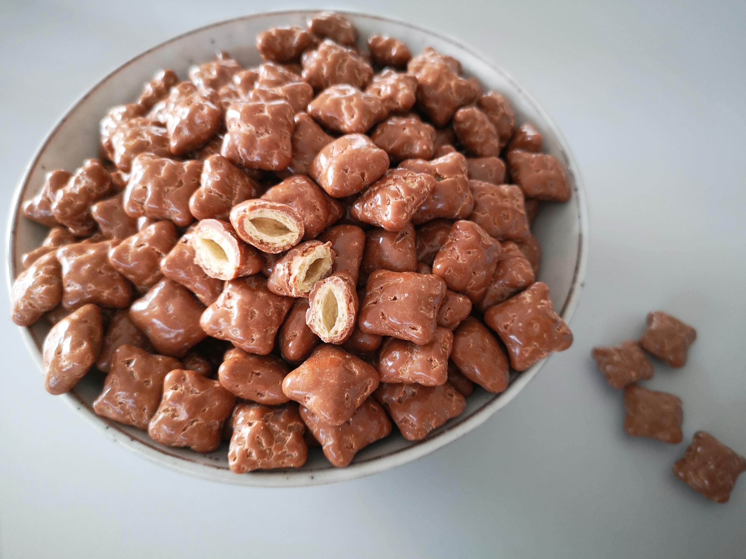 a bowl of chocolate covered pretzels with one being cut in half