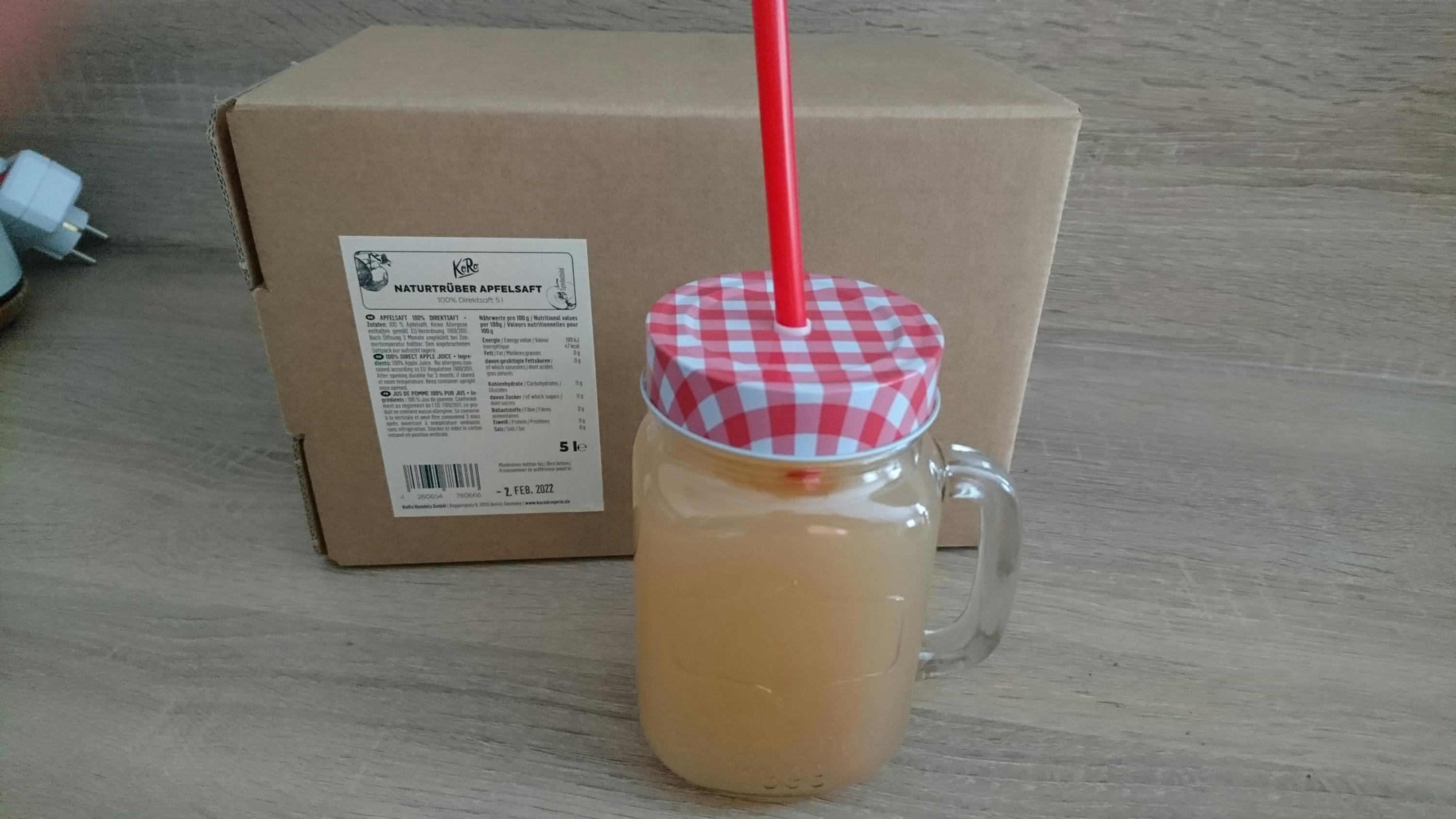 une bouteille de jus de pomme avec une paille à côté d' une boîte de jus de pomme