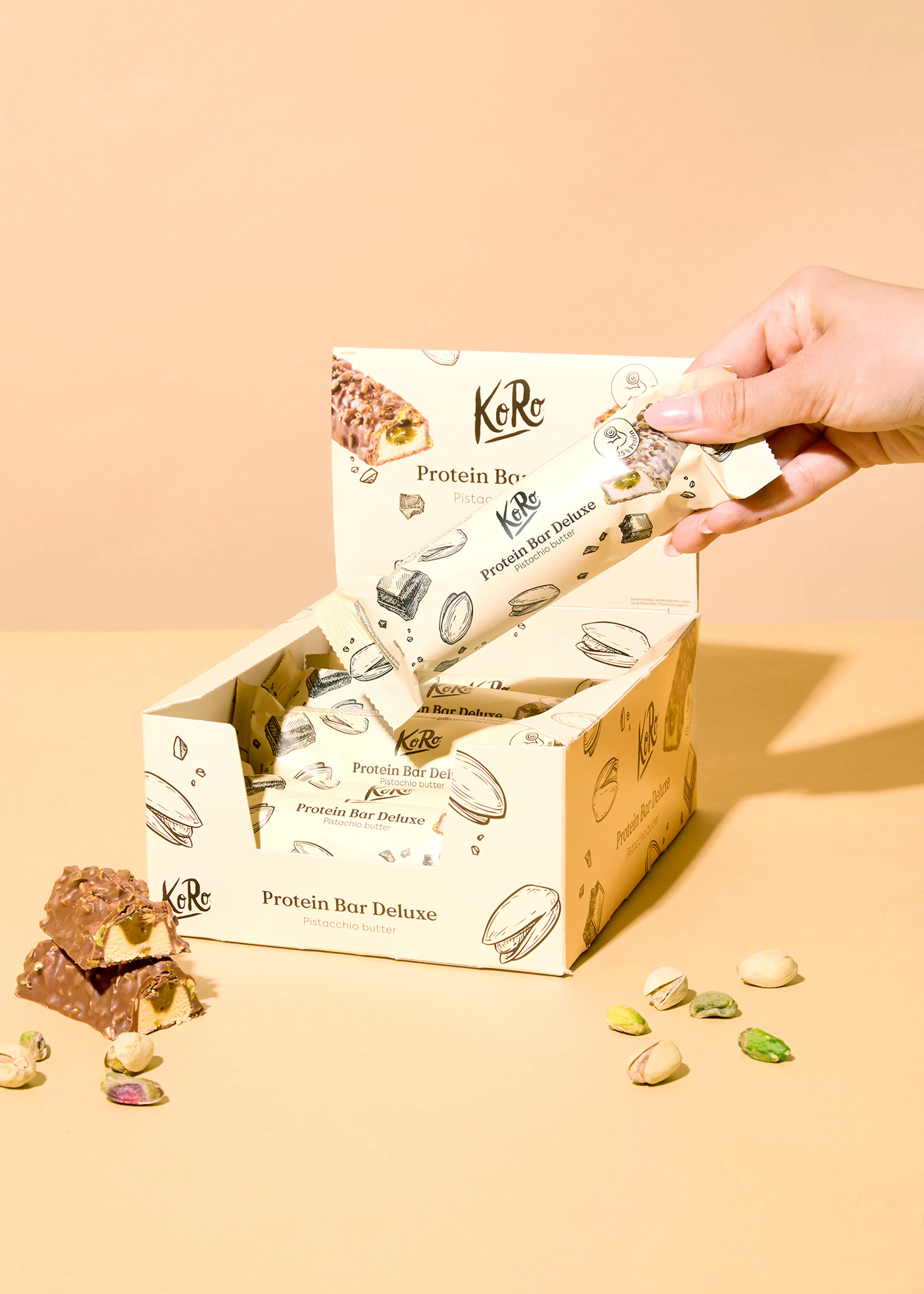 eine hand hält einen protein bar deluxe aus einer box