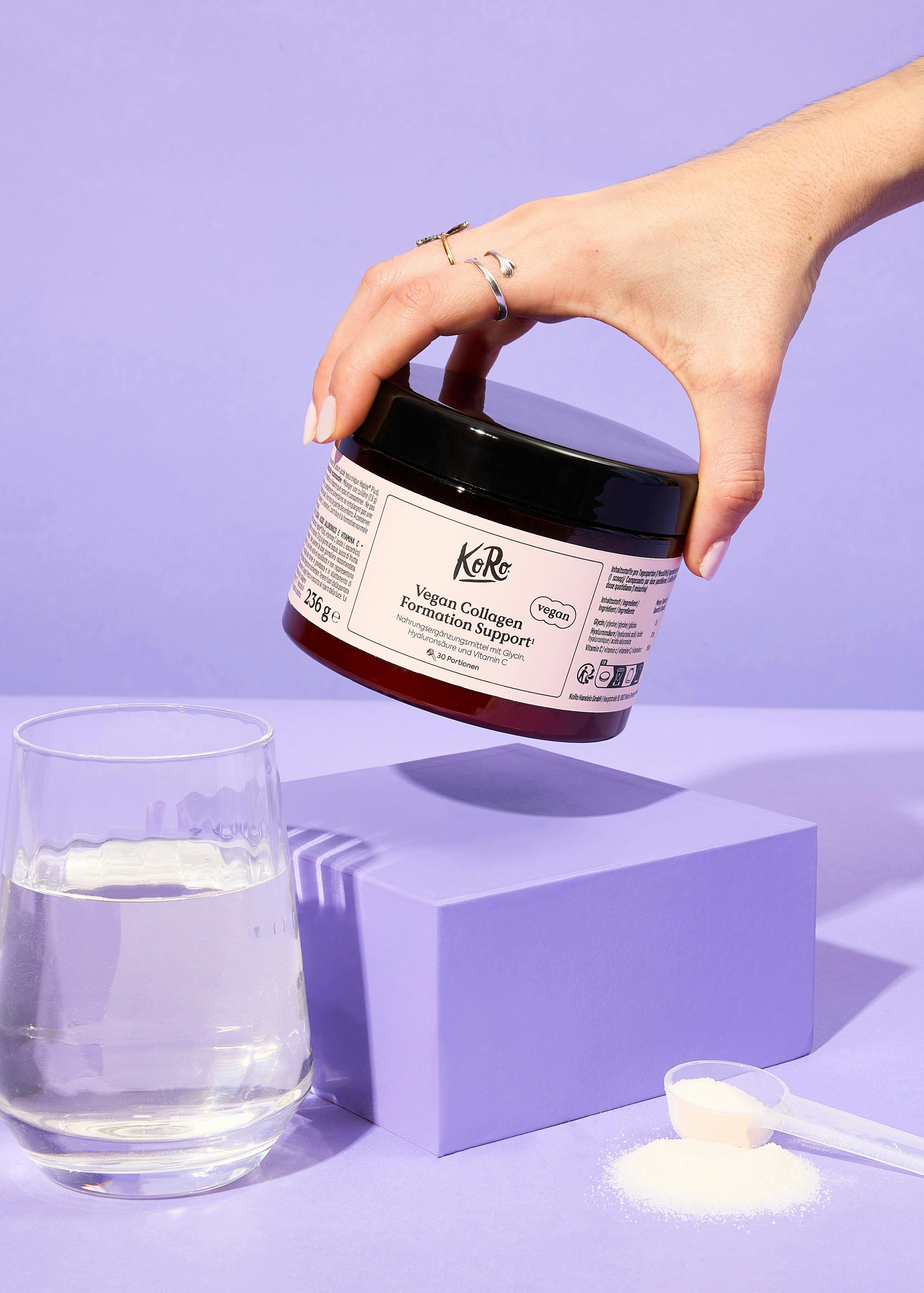 eine Frau gießt etwas aus einem Kori-Produkt in ein Glas Wasser